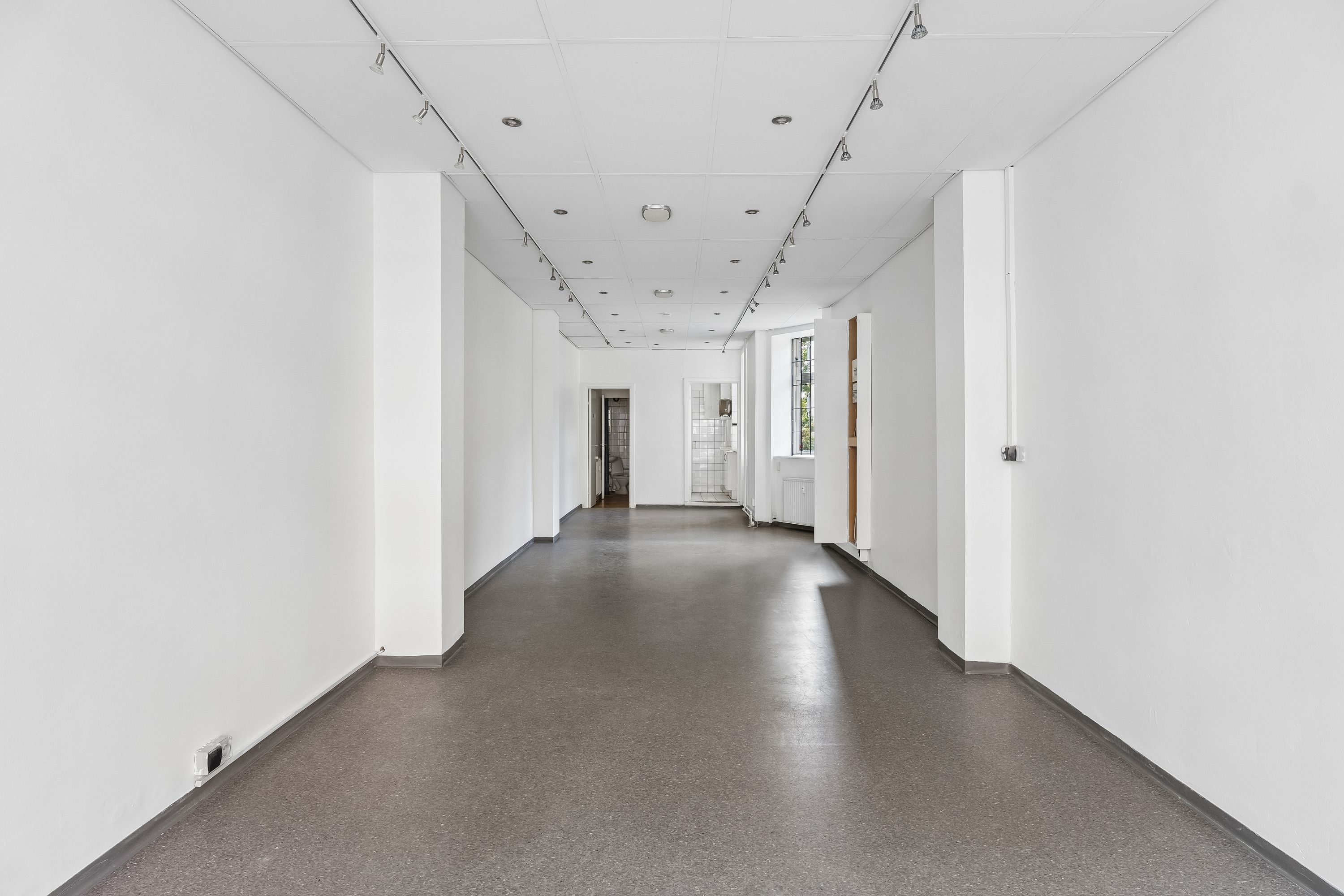 Kort og enkelt, men luksuriøst og stilfuldt, indre butikslokale til leje. Lys, rent og moderne med højt til loftet og glasvinduer. Perfekt til butiksforretning.
