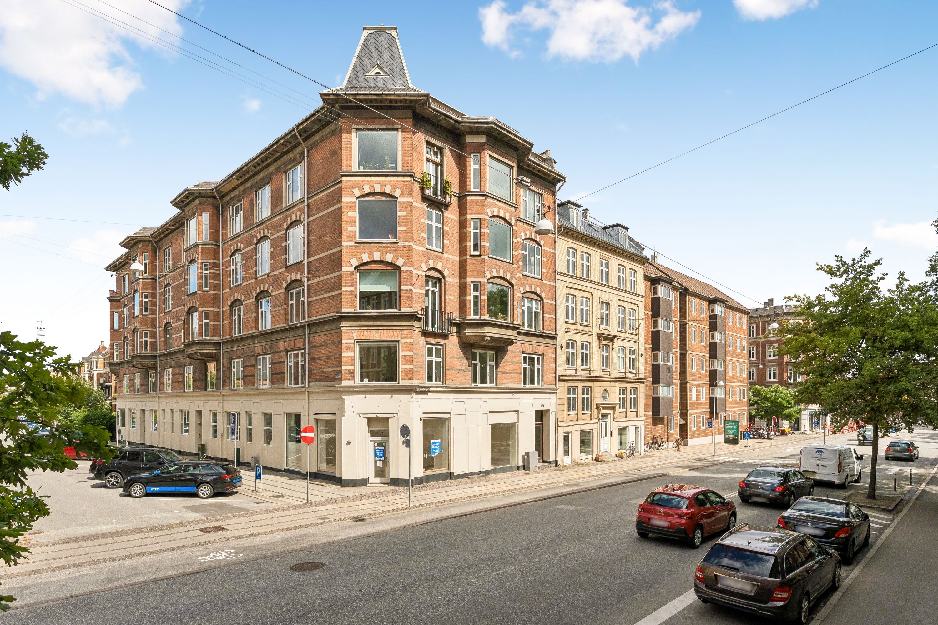 Mange biler kører langs Vesterbrogade i Frederiksberg C, hvor der er parkerede biler og grønne træer langs fortovet
