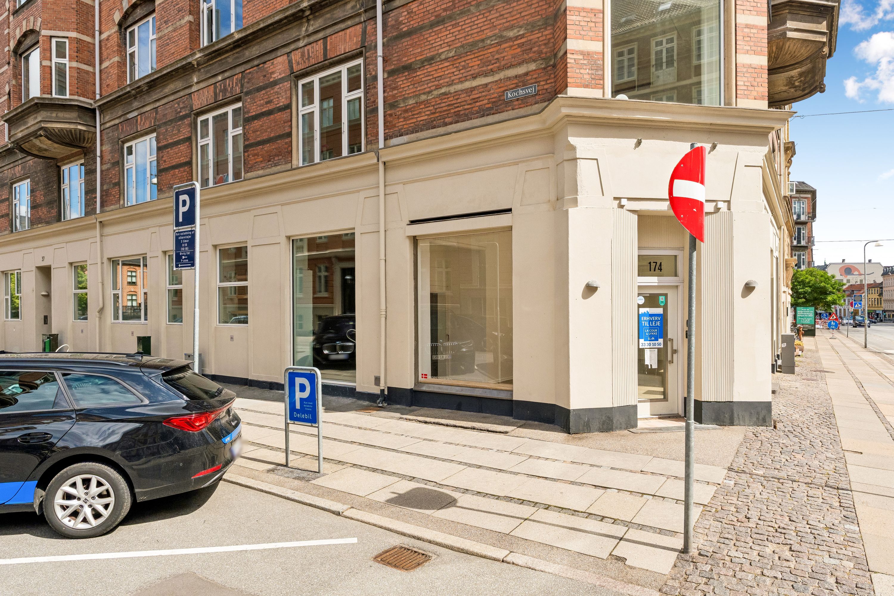 Lejlighed til leje på Vesterbrogade i Frederiksberg. Køkkensvej 174 og Parkeringszone foran bygningen. Søjle med skilt og nummer 174 samt bilparkeret foran.