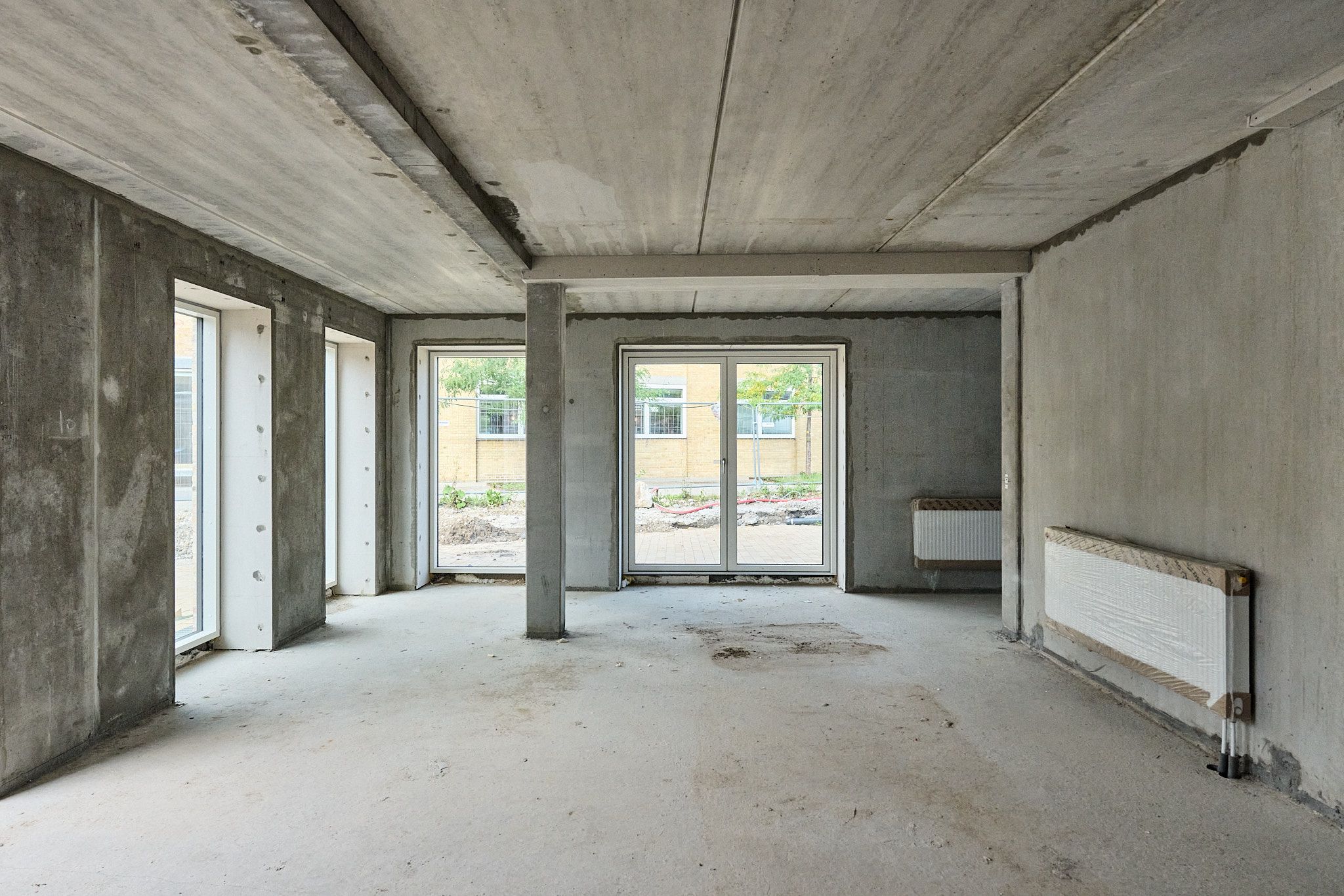 Moderne erhvervslejemål med glasdøre, vinduer, to radiatorer og høje betonvægge