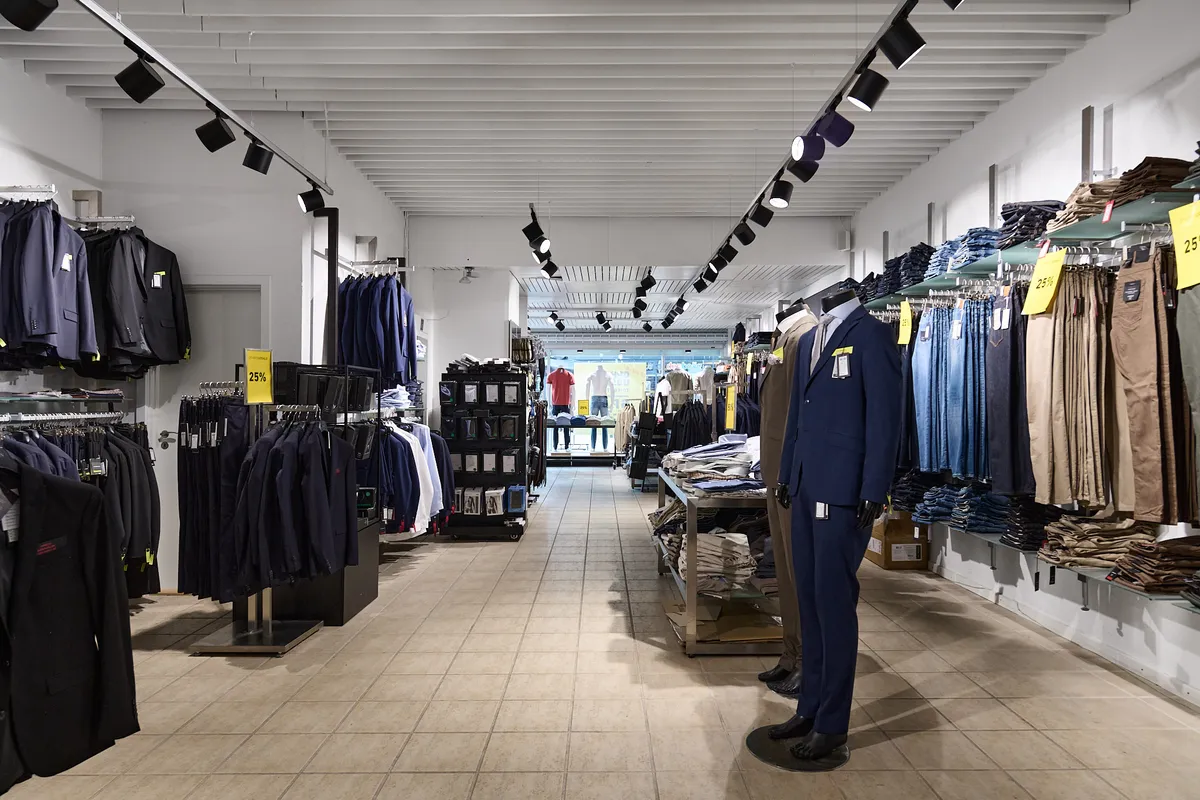 Butik med mænds og kvinders tøj, lyse taklamper og 25% rabat-skilting.