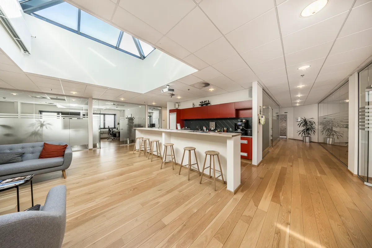 Luksuriøs lobby med højt loft, lyskryds, lyse pladelofter og glasvægge og stolpe med sofa og bord med tidsskrifter