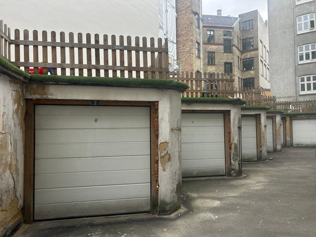 Garage med nummer 2, placeret i en lukket gård på Vesterbro, med flere garager og en skur bagved, hus med flere etager og vinduer