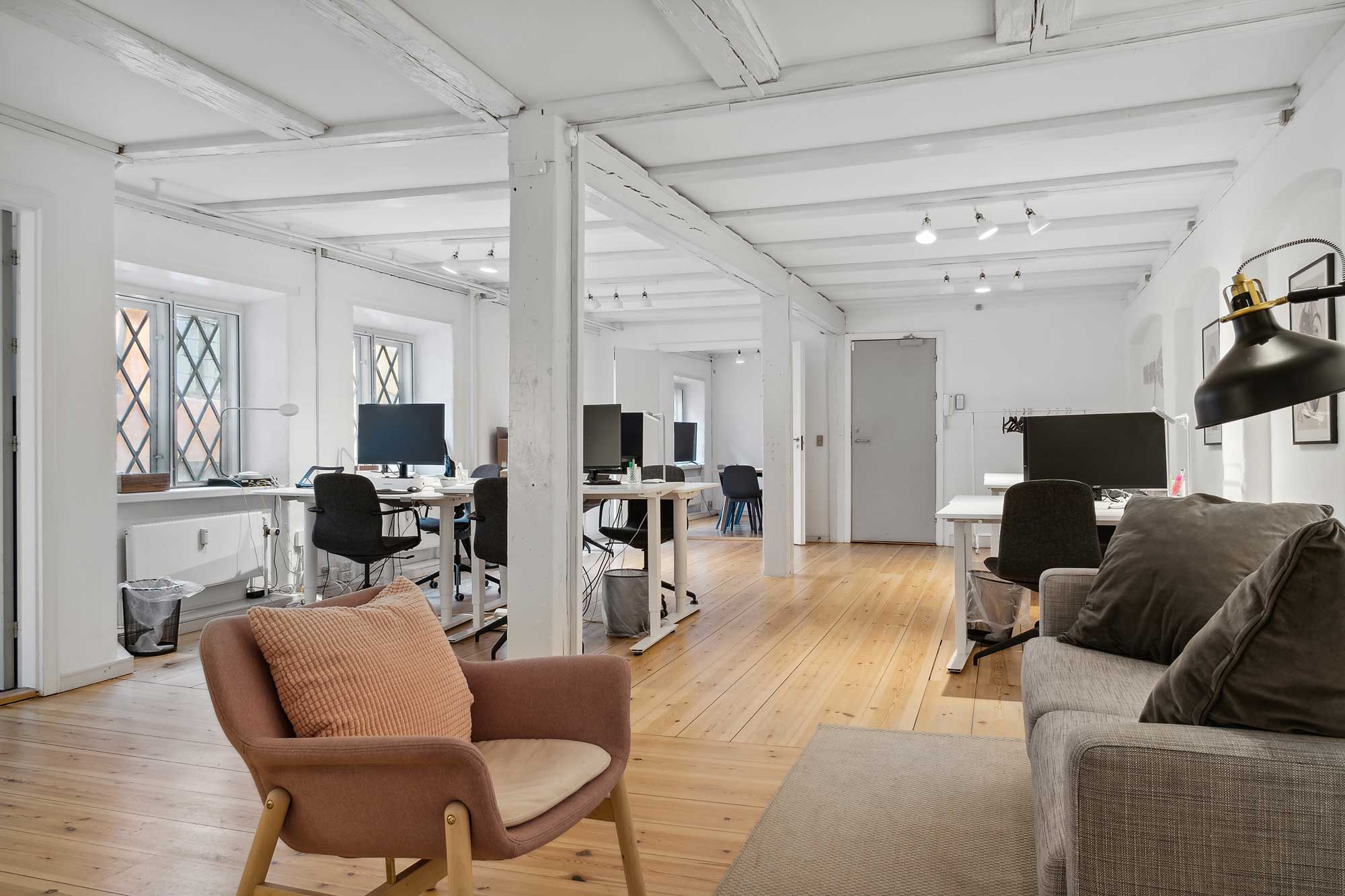 Kontorrum med højt til loftet og møbler i minimalistisk stil, højt til loftet med hvide loftbjælker og moderne møbler