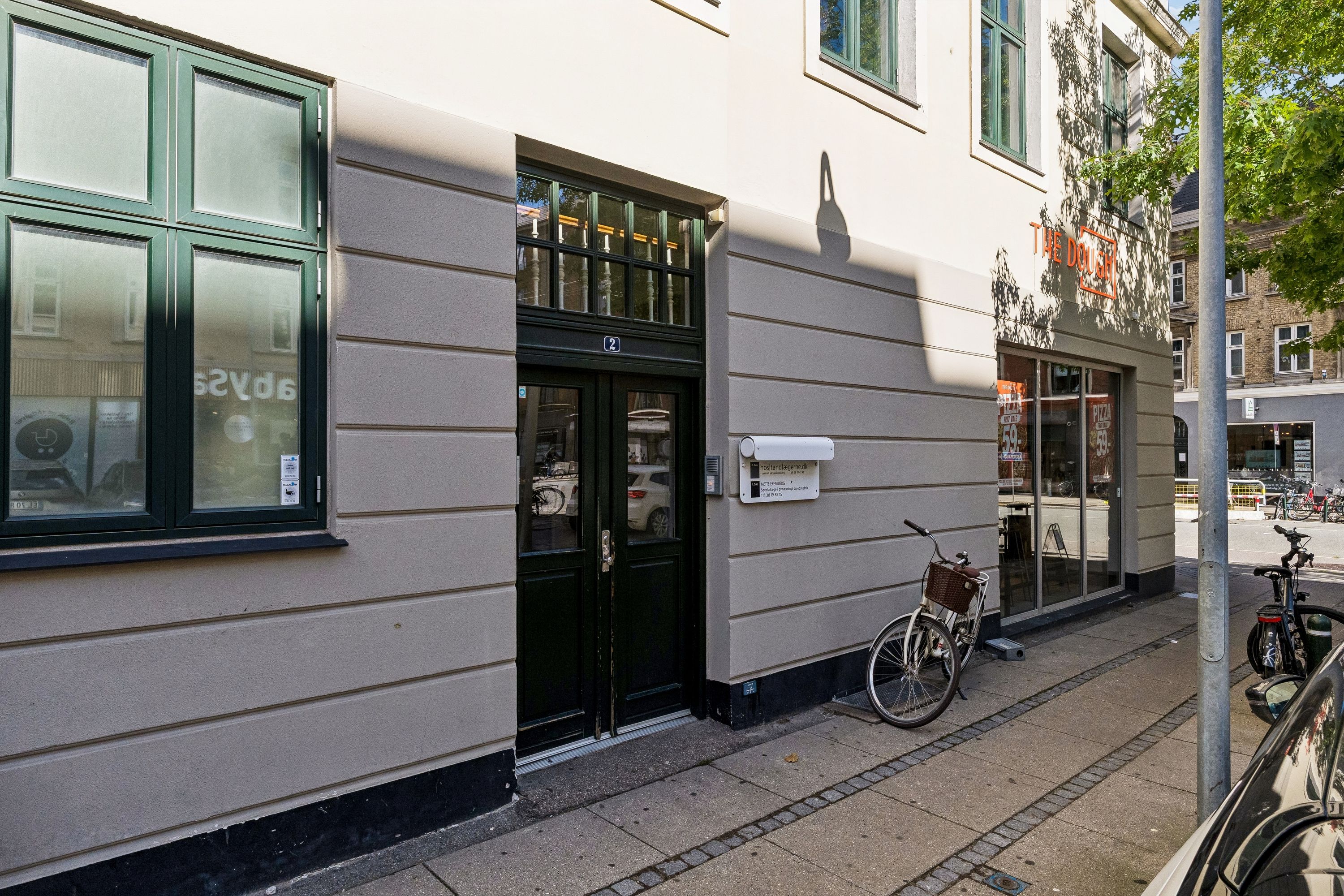 Kontor til leje på Roarsvej 2 i Frederiksberg med masser af lys, to døre, og en cykel parkeret udenfor.