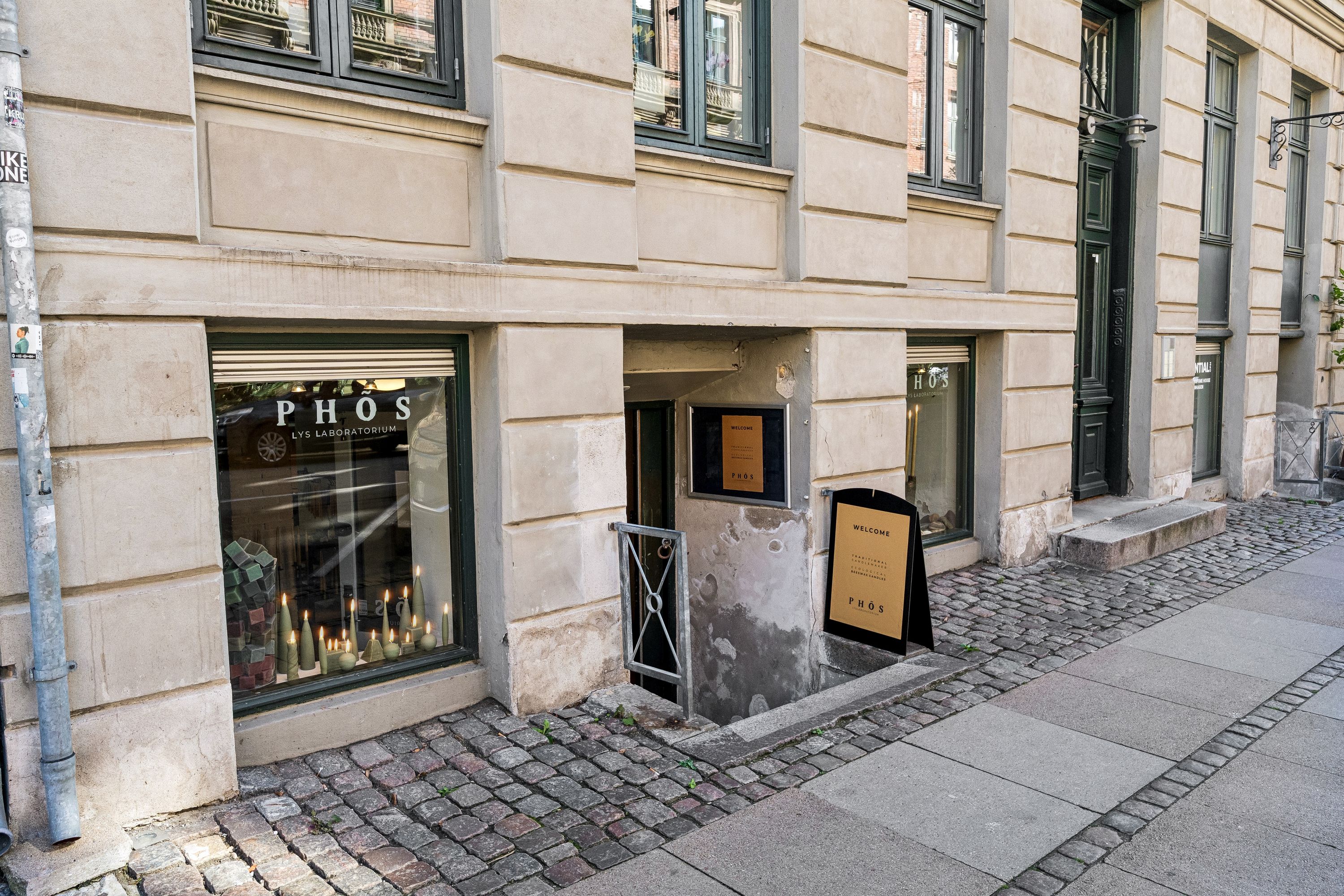 Kælderleje på Nansensgade med lyslaboratorium, lysekroner og en velkomstskilt, der læser "PHOS" og "WELCOME"
