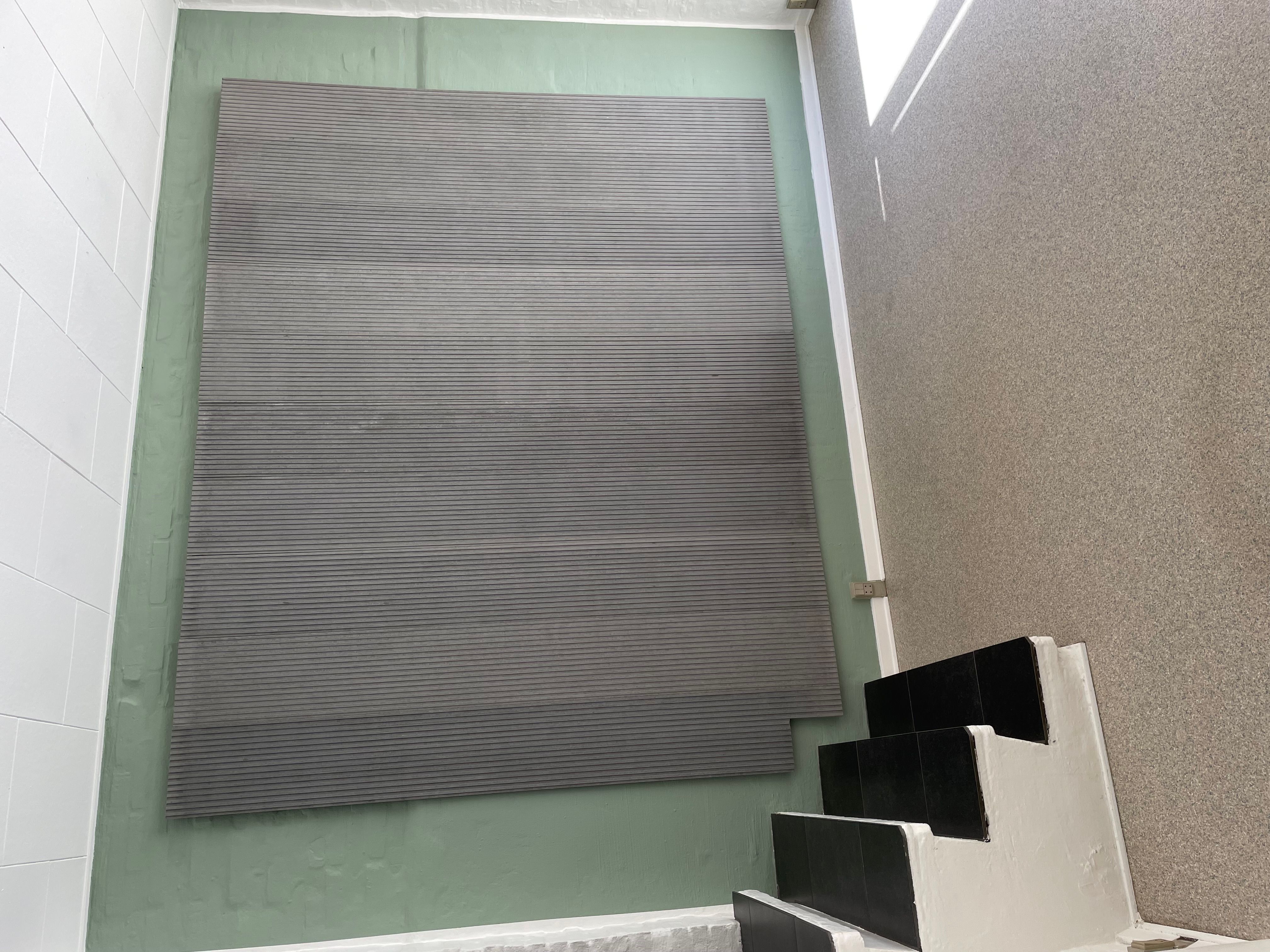 Stairs og grøn væg med gulvbelægning i stribet træmateriale. To stribede gulvbelægningsplader ligger på væggen og er ikke endnu monteret