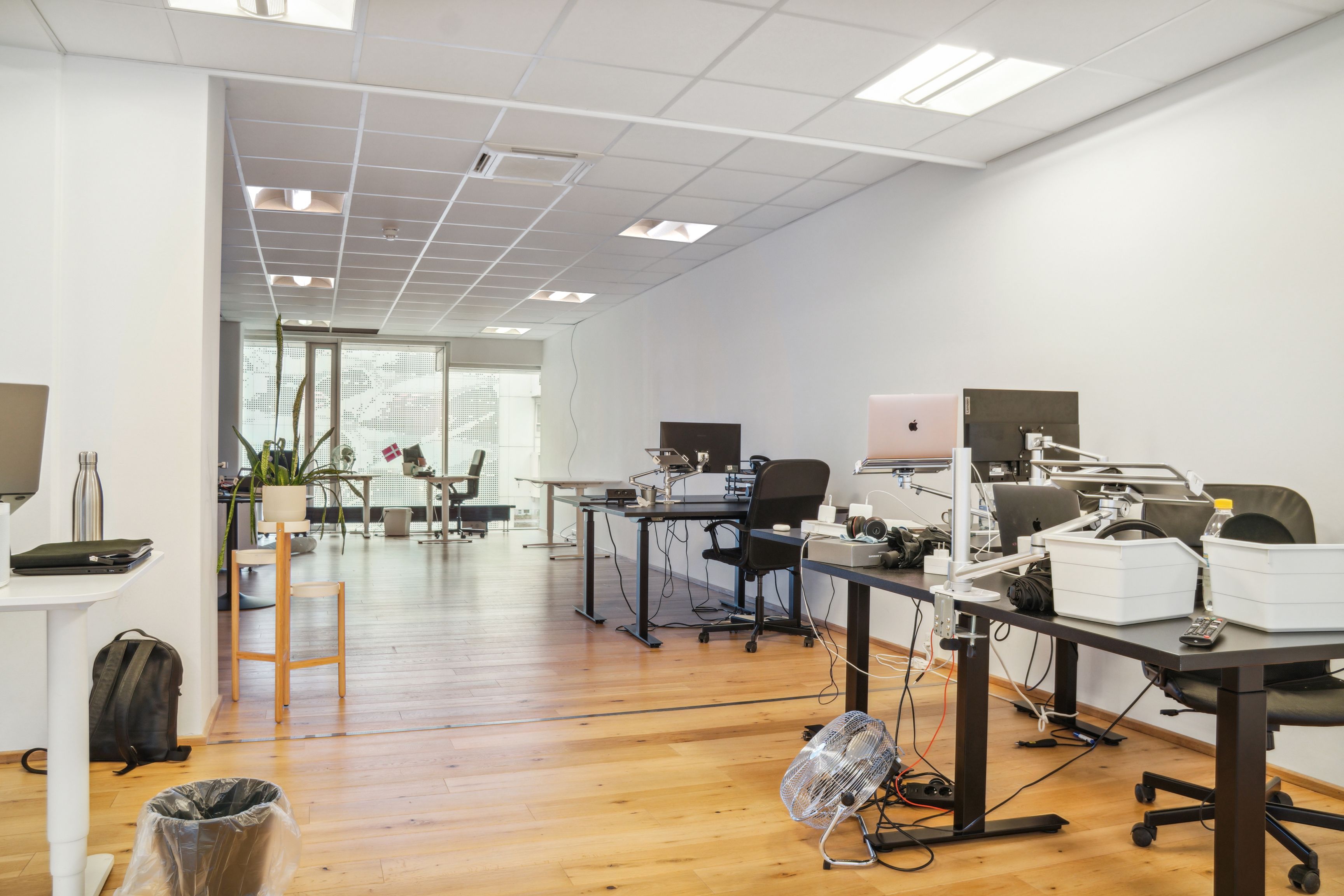 En stor kontor med højt loft, flere bord og stole samt en række monitorer og apparater
