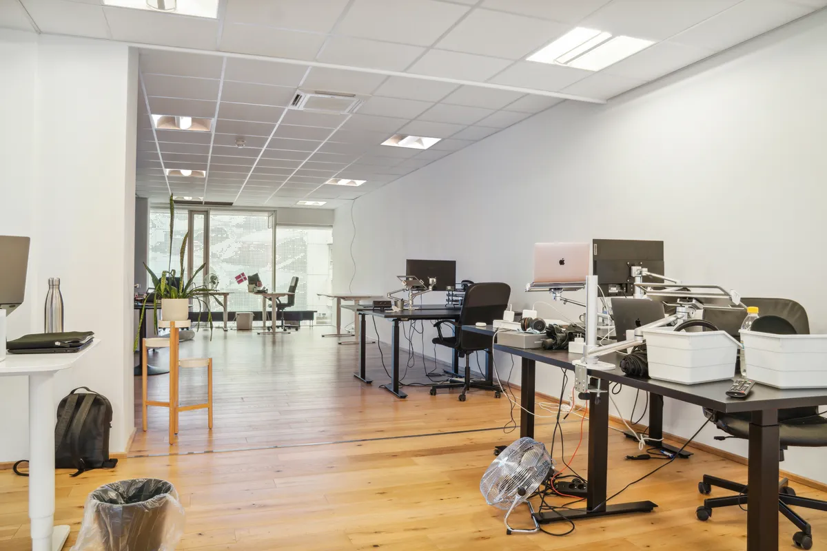 En stor kontor med højt loft, flere bord og stole samt en række monitorer og apparater