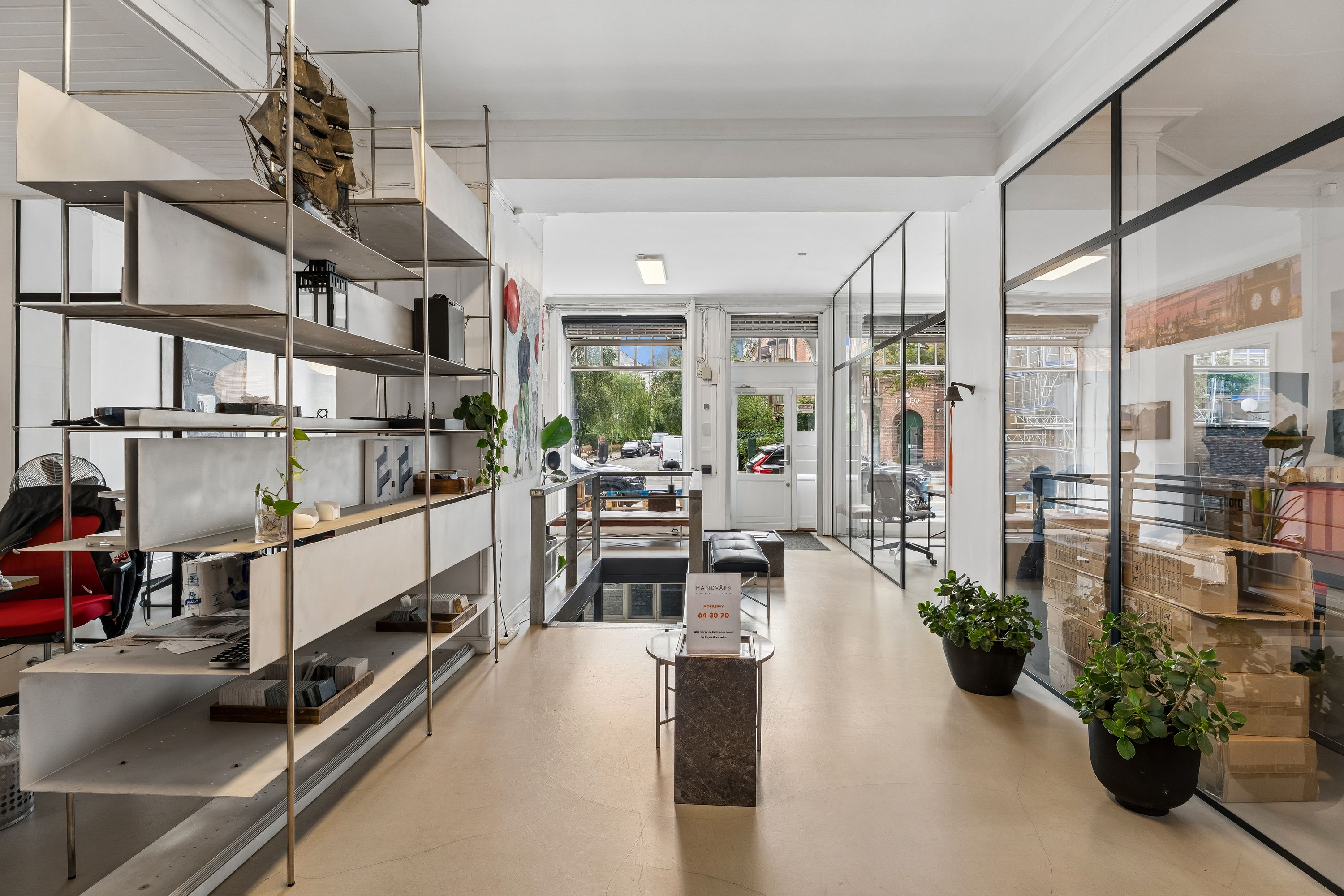 Butik med moderne møbler, plantepots og smykkeudstilling i en stor og rummelig lokale med store vinduer og høj synlighed