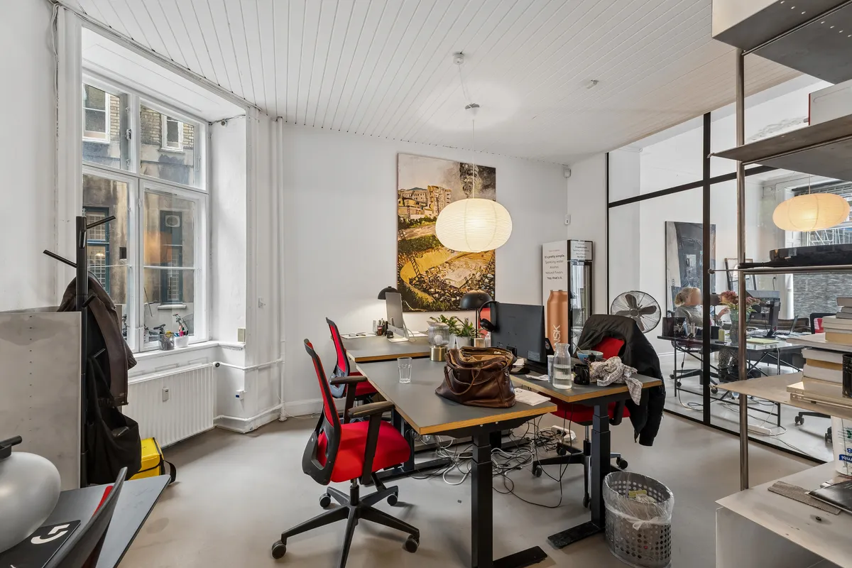 Kontor med høj synlighed på Vesterbrogade 196, st. th. Erhvervslejemål med store vinduer og lyse lofter. Kontorbord med computer og lyse stolpelampe i det åbne rum