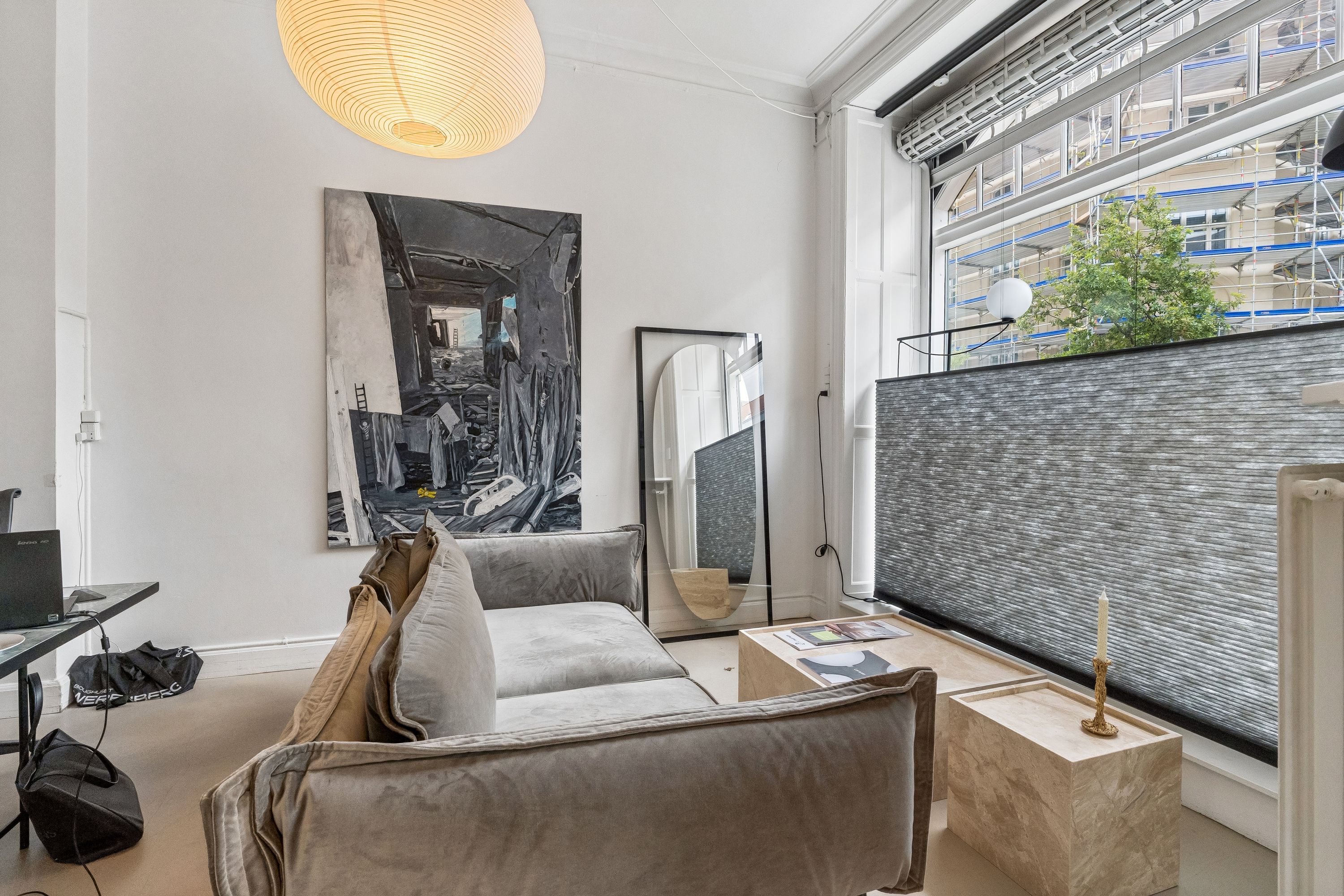 På Vesterbrogade 196 udbydes et moderne lejemål med stort vindue, gulvtæppe, sofa og skråt hængende billede i minimalistisk interiør