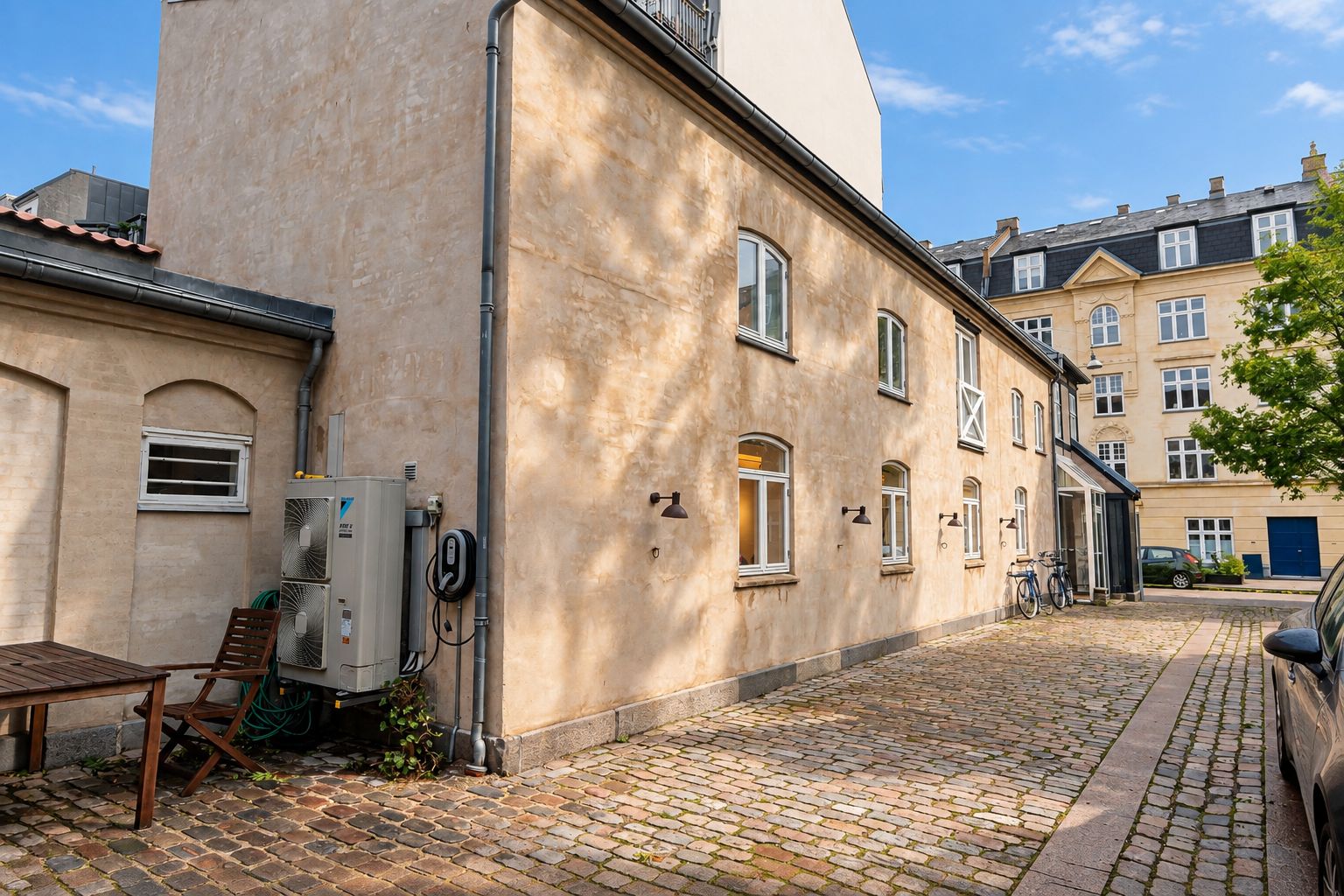 Grønne og lyse vinduerne reflekterer sollyset, og der er flere vinduer på bygningen. Der er to både parkeret og to stolpelampe. Der er en skovl og et klimaanlæg.
