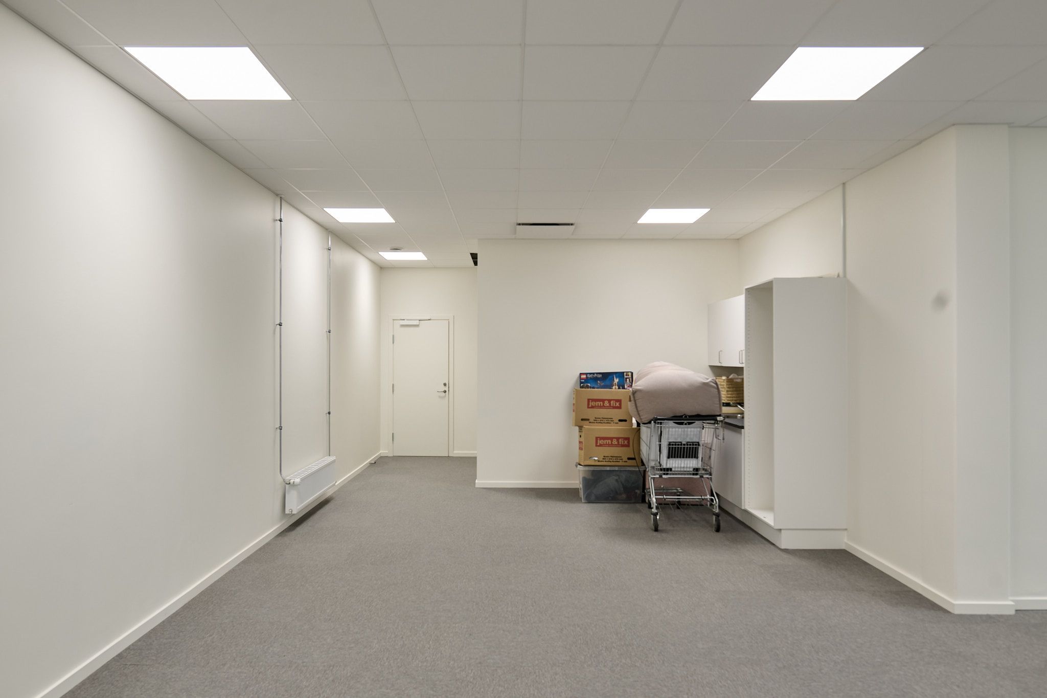 Lyserummet med to hvide vægge, et gulvtæppe og fire højre bokse er forbundet med to hvide høje og en høj stol. Fire hvide loftslampe er installeret på loftet