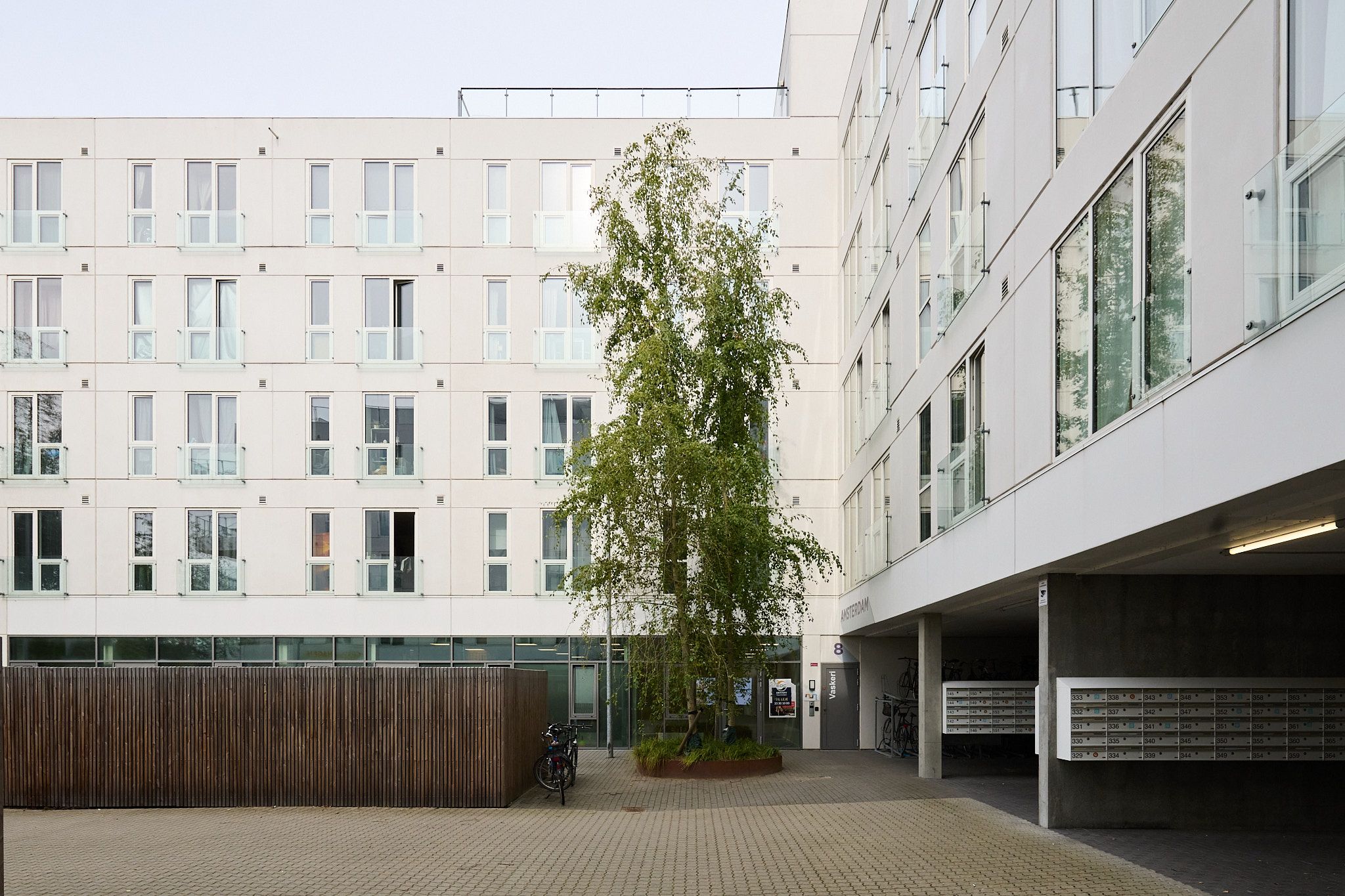 På Poppelstykket 8A i København SV findes et velbeliggende erhvervslejemål med funktionelle faciliteter. Her er en stor træskur, parkeringsplads og park. Bygningen er hvid med glasruder og balkoner
