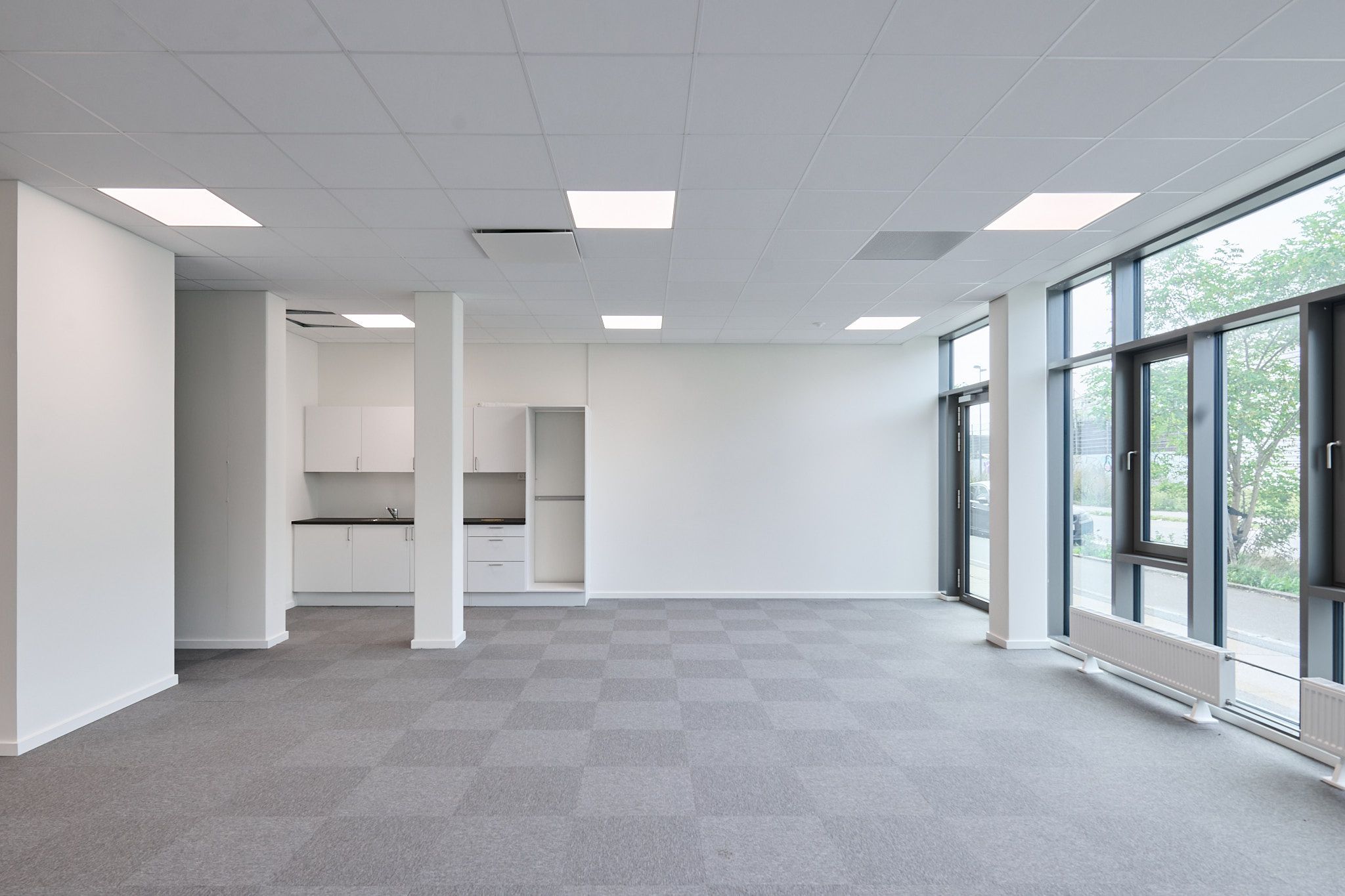 Rummelig og lys kontorer med store vinduer og moderne design. Hvidt loft med indbygget belysning og smukke tæpper. Værelse med garderobe og køkkenområde.