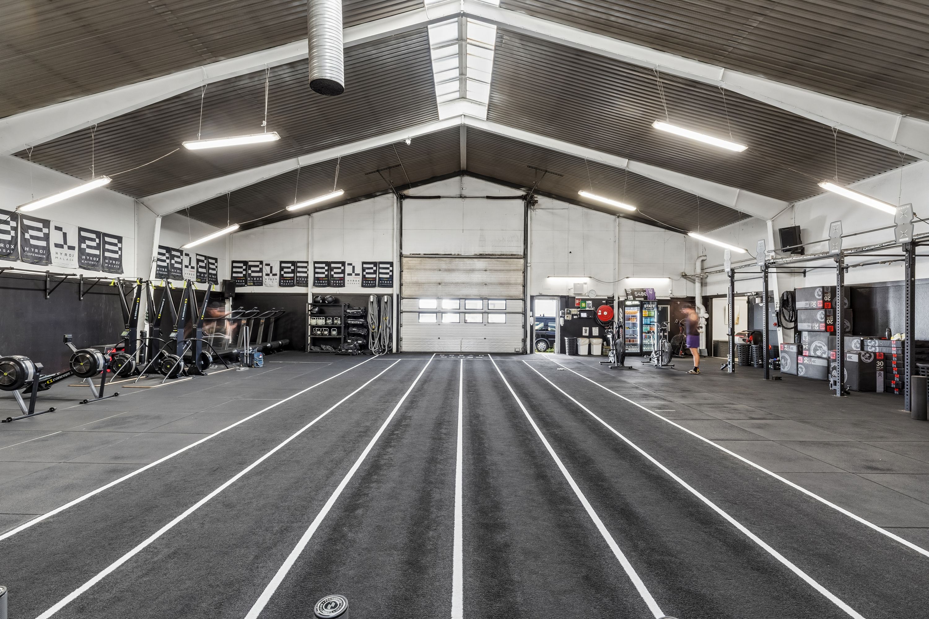 Et stort, lyst, renset og rummeligt lager med høje lofter, flere gulvmonterede fitnessapparater og en løbebane på gulvet