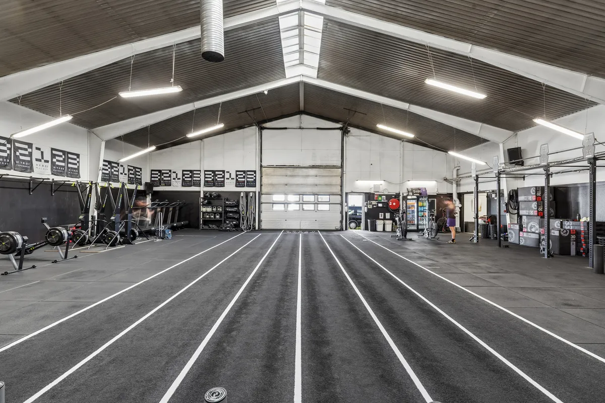 Et stort, lyst, renset og rummeligt lager med høje lofter, flere gulvmonterede fitnessapparater og en løbebane på gulvet