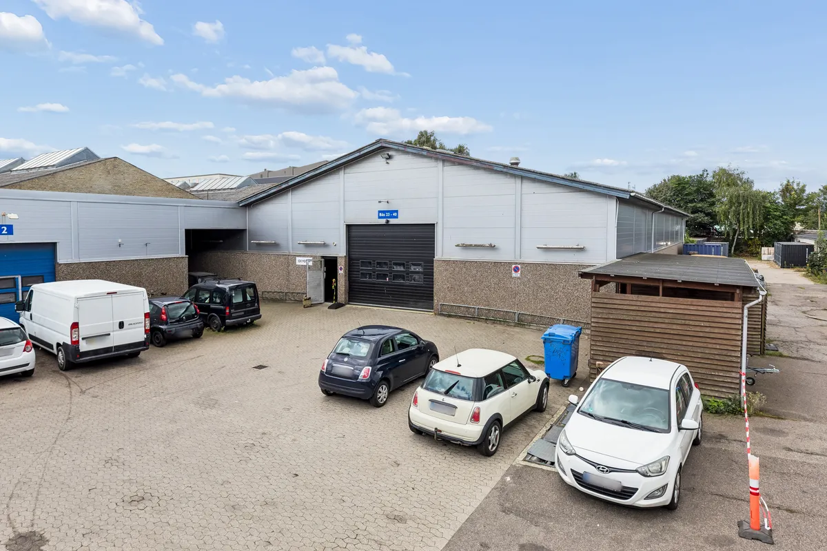 Et lager med garage og stor parkeringsplads for biler, lastbiler og servicekøretøjer