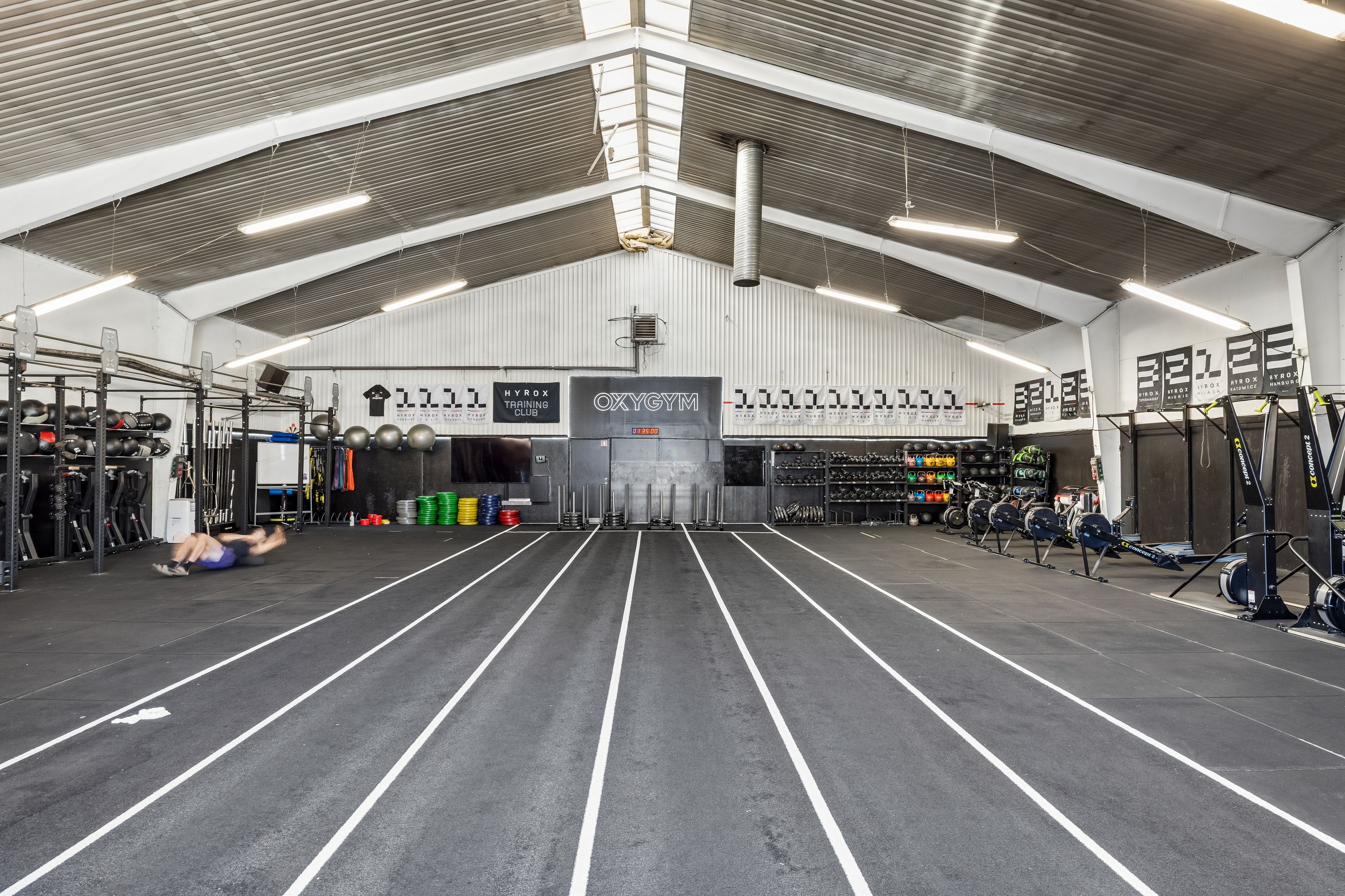 Højloftet lager til leje med gulvspor, fitnessapparater og vægbanners, der lægger op til træningsophold i 2450 København SV