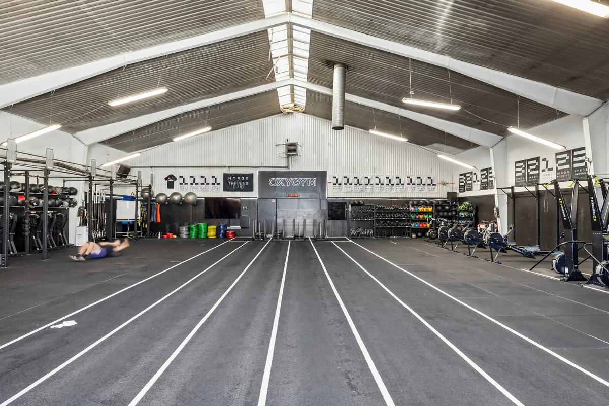 Højloftet lager til leje med gulvspor, fitnessapparater og vægbanners, der lægger op til træningsophold i 2450 København SV