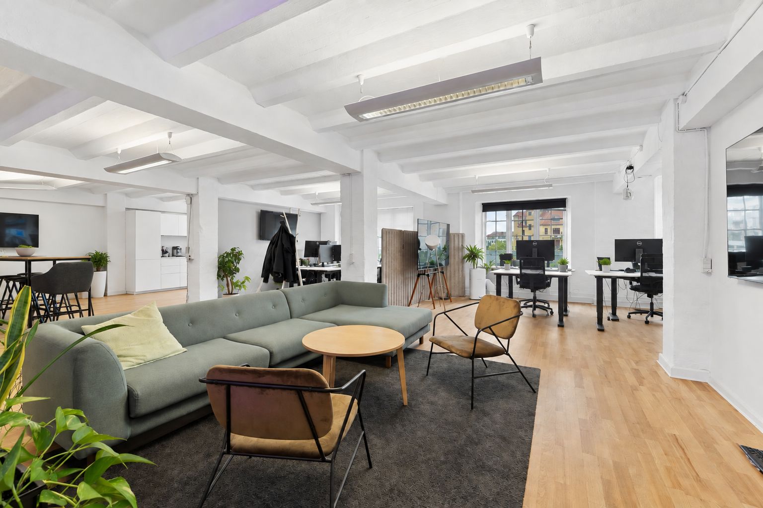 Kontorlokaler med åbne arbejdsområder og møderum til leje i København. Køkken med moderne apparater og møbler. Lyse lofter og trægulve.