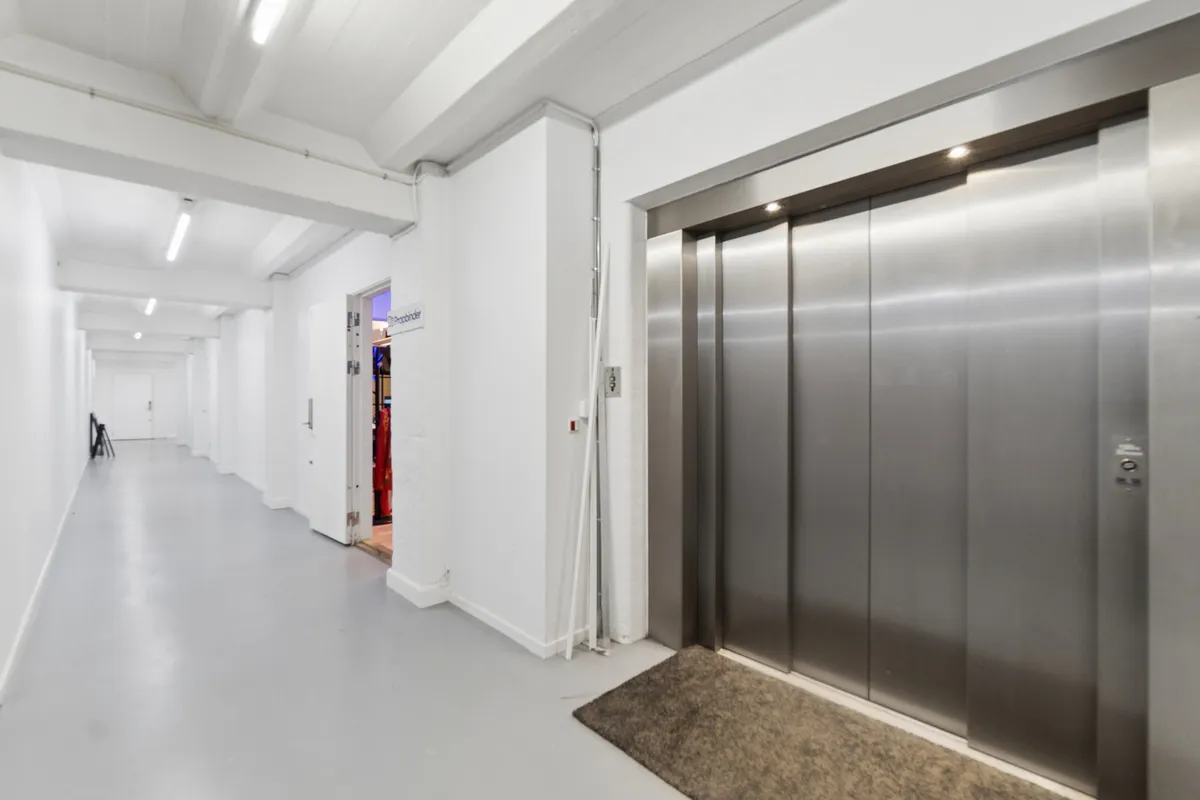 Lyst og moderne kontorlokal i København med elevator, åbne arbejdsområder og mødefaciliteter, lette gulve og lyse vægge
