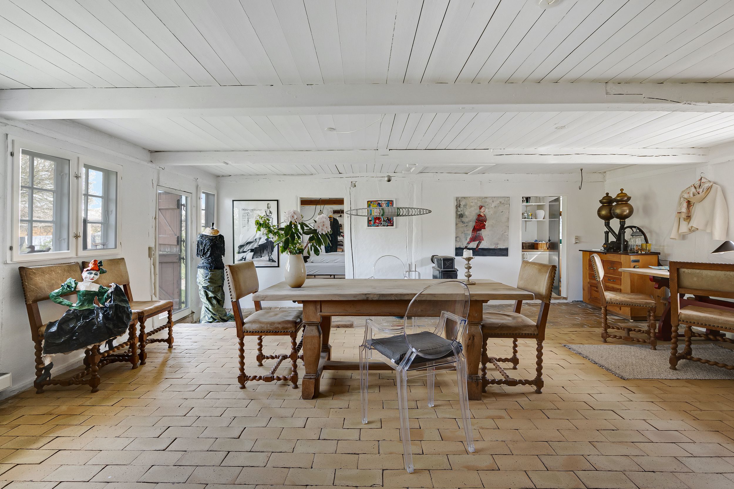 Interiør med lyse vægge og trægulve og træbord med lyse stolen og tydelige møbler og kunstværker og en statue og et træskab