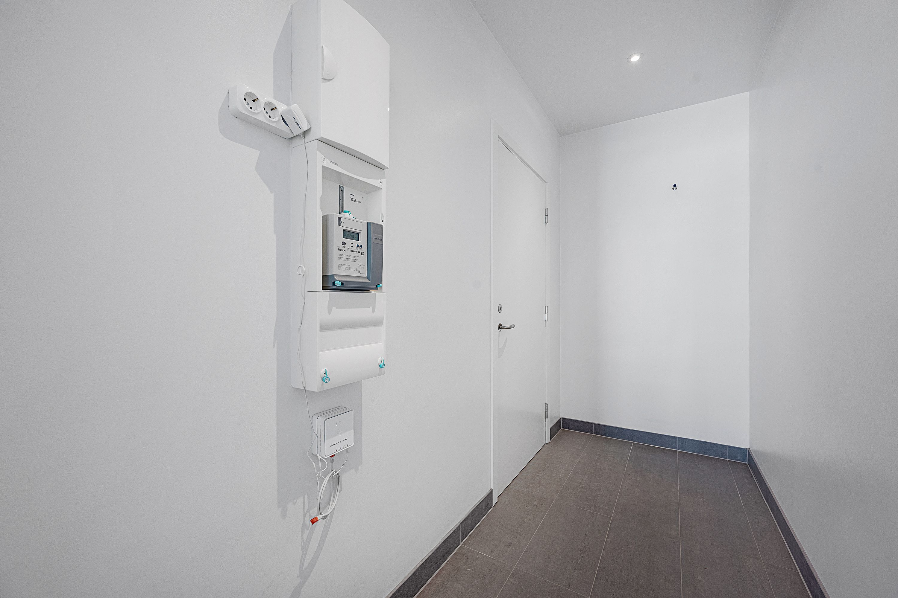 En hvid væg med elektriske stikkontakter og en dør med sølvfarvet håndtag i en lejlighed