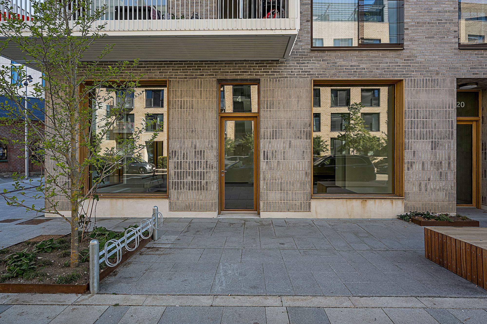 Et moderne lejemål med tre vinduer og en hoveddør og en have med grønne planter og en lille træ på Frederiksberg