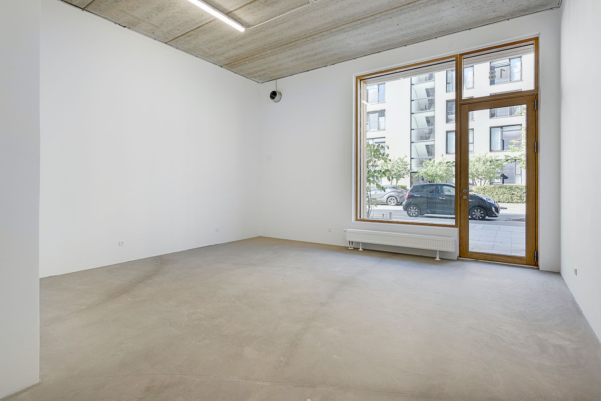 Lejlighed med en stor vinduesfront og åben dør, lysegul gulv og hvide vægge