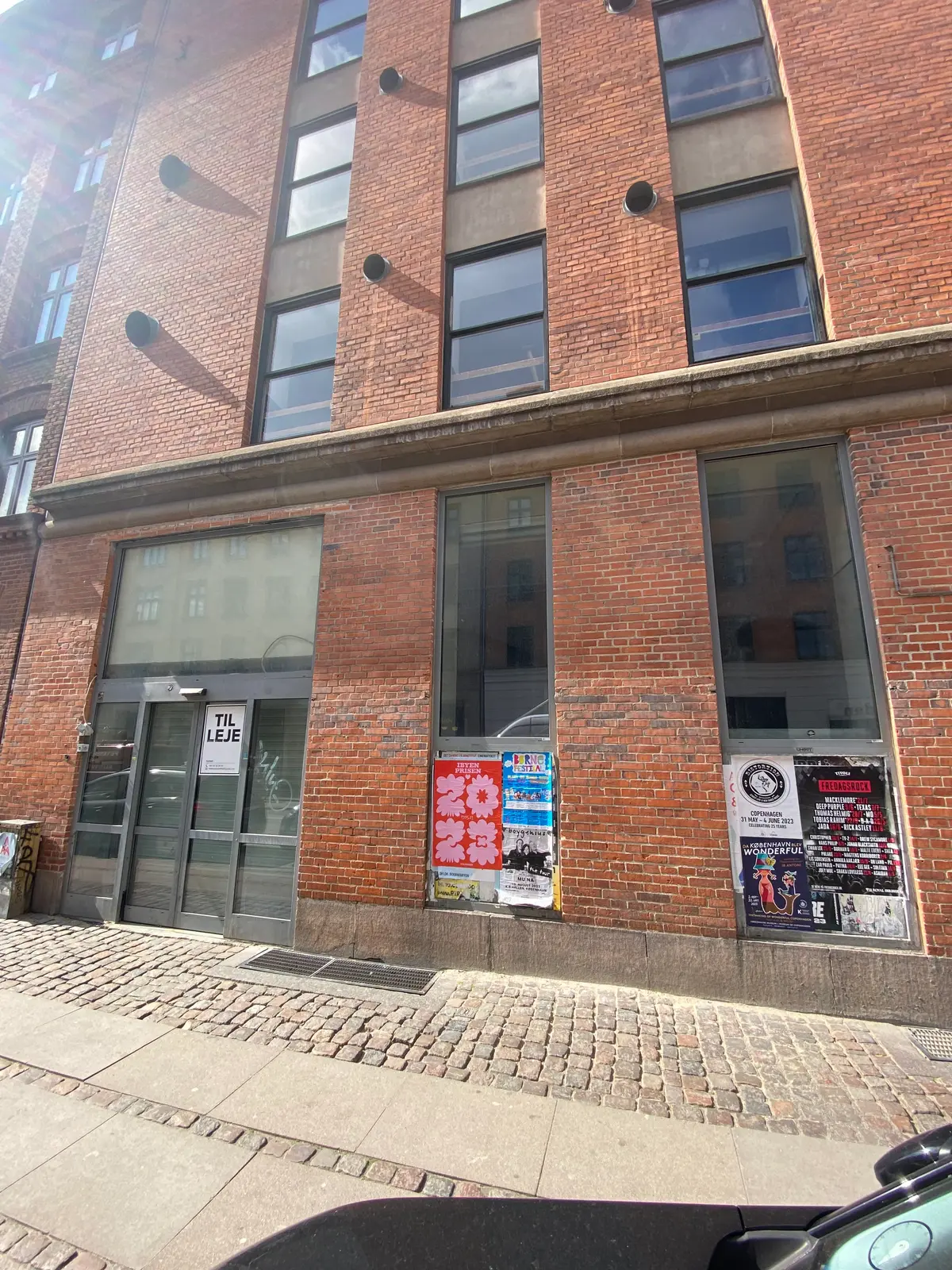 Bryggergården er på Vesterbro og har store glasruder og røde mursten. Værelserne er til leje og der er reklamer klistret på