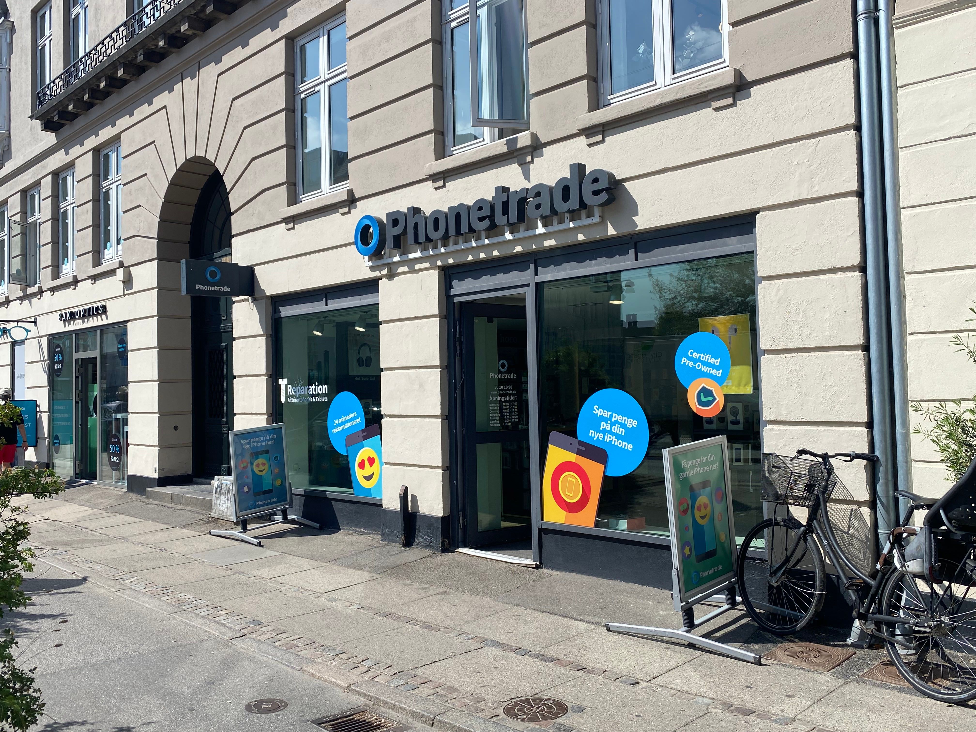 Phonetrade butik med en kæde på cykel og et skilt med ordet reparation og reklame for iPhone på facaden