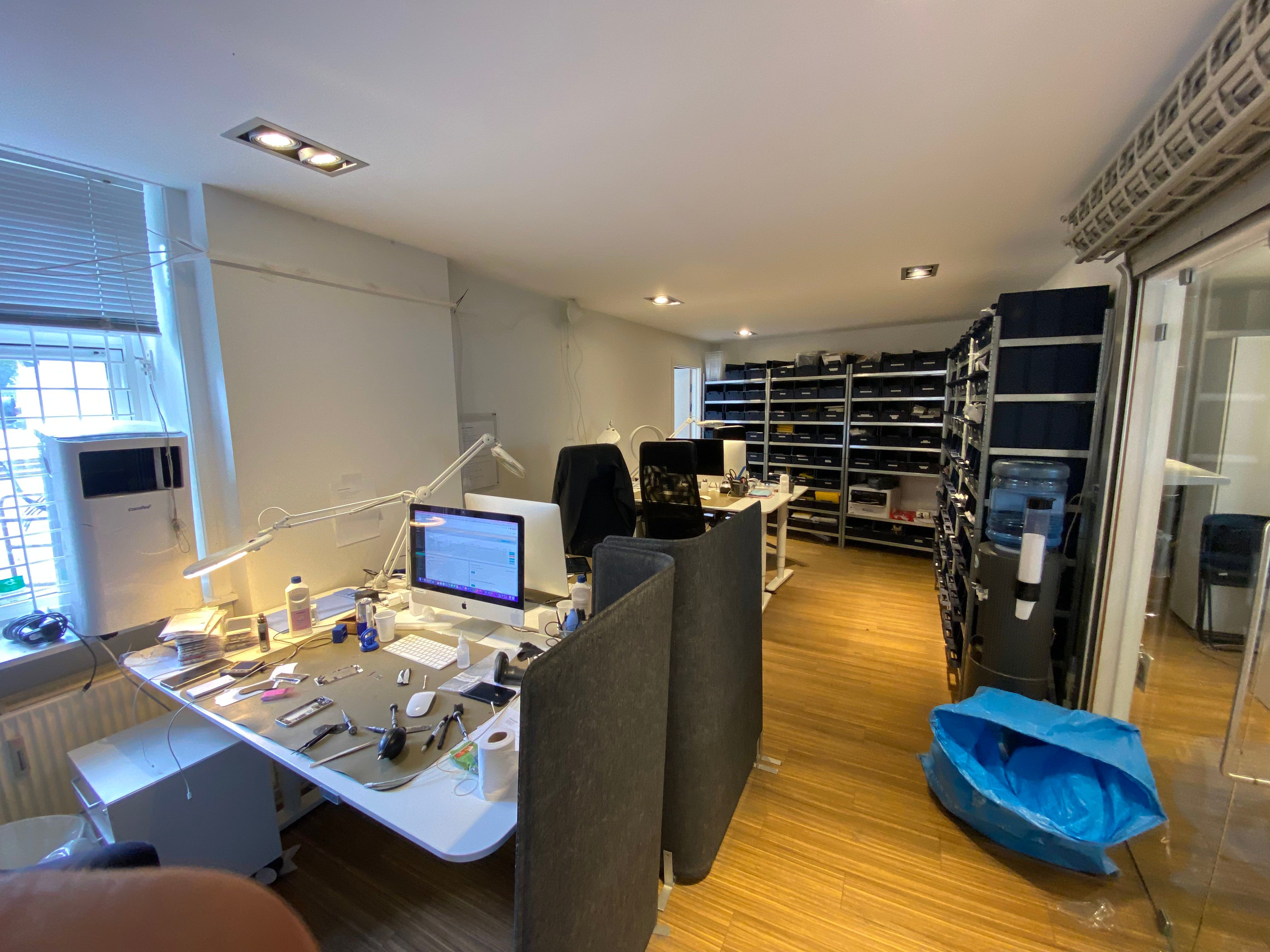 Kontorrum med to skriveborde, computere, og diverse elektronik. På gulvet er en håndtaske og et sæt værktøj. På det ene