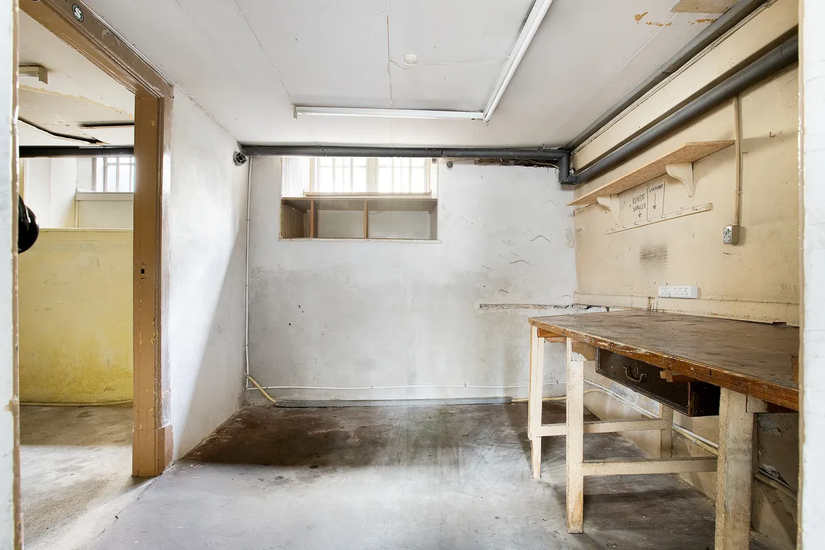 Værelse med lyse og røde vægge og gammelt træbord og beklædningshylde i loftet