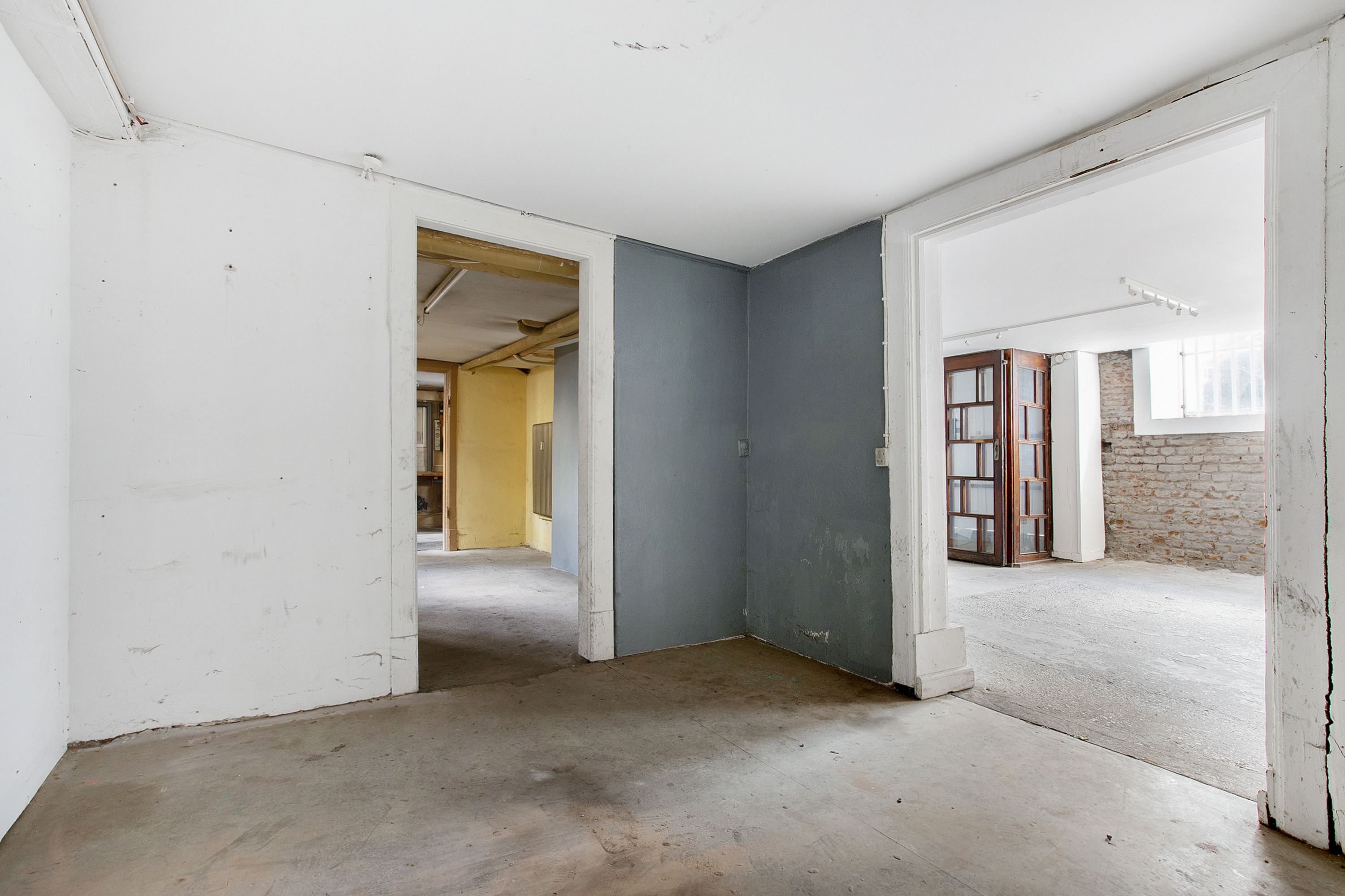 Foto af en tom, ubeboet rum med tømmerklodser og lysekroner, uden møbler og inventar