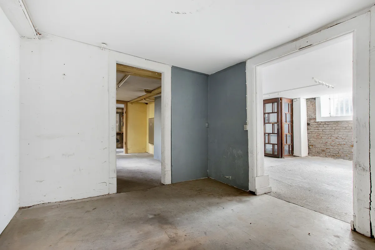 Foto af en tom, ubeboet rum med tømmerklodser og lysekroner, uden møbler og inventar