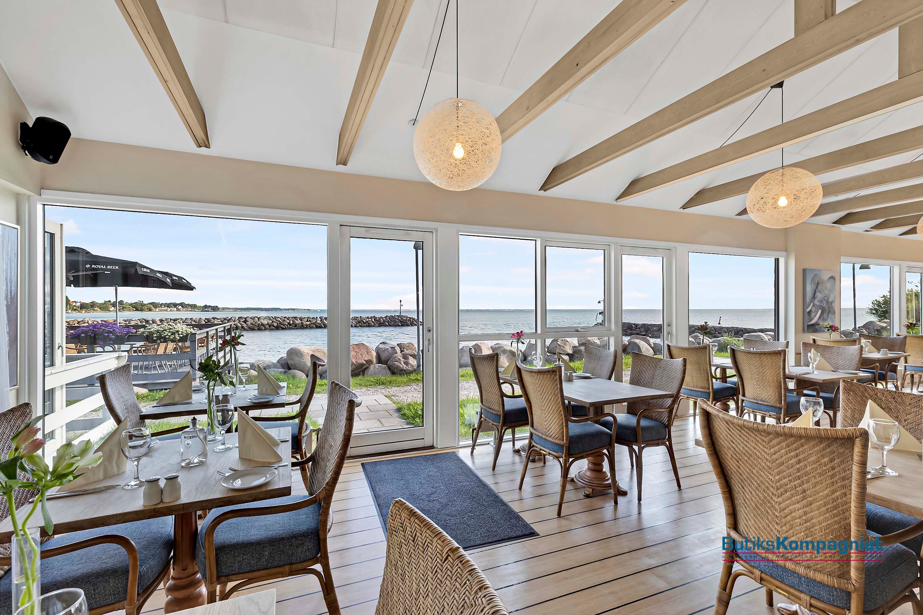 Glasser, servietter og vinglas på et bord med udsigt til havnen i Nivå