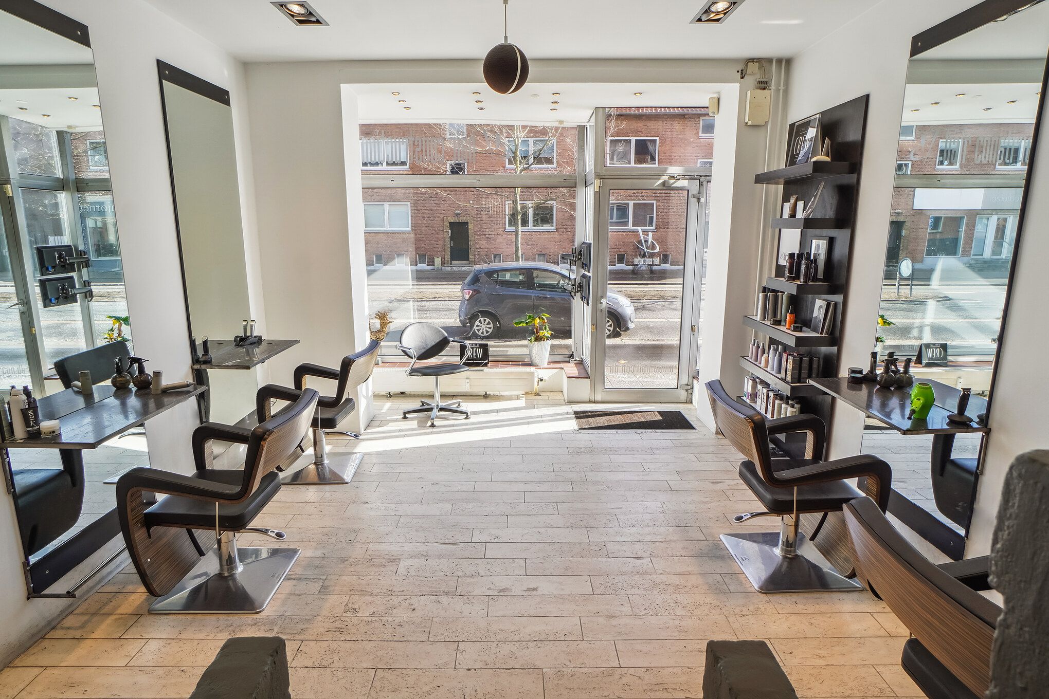 Frisørsalon med trægulve og moderne interiør med lyse højhylder og spejle