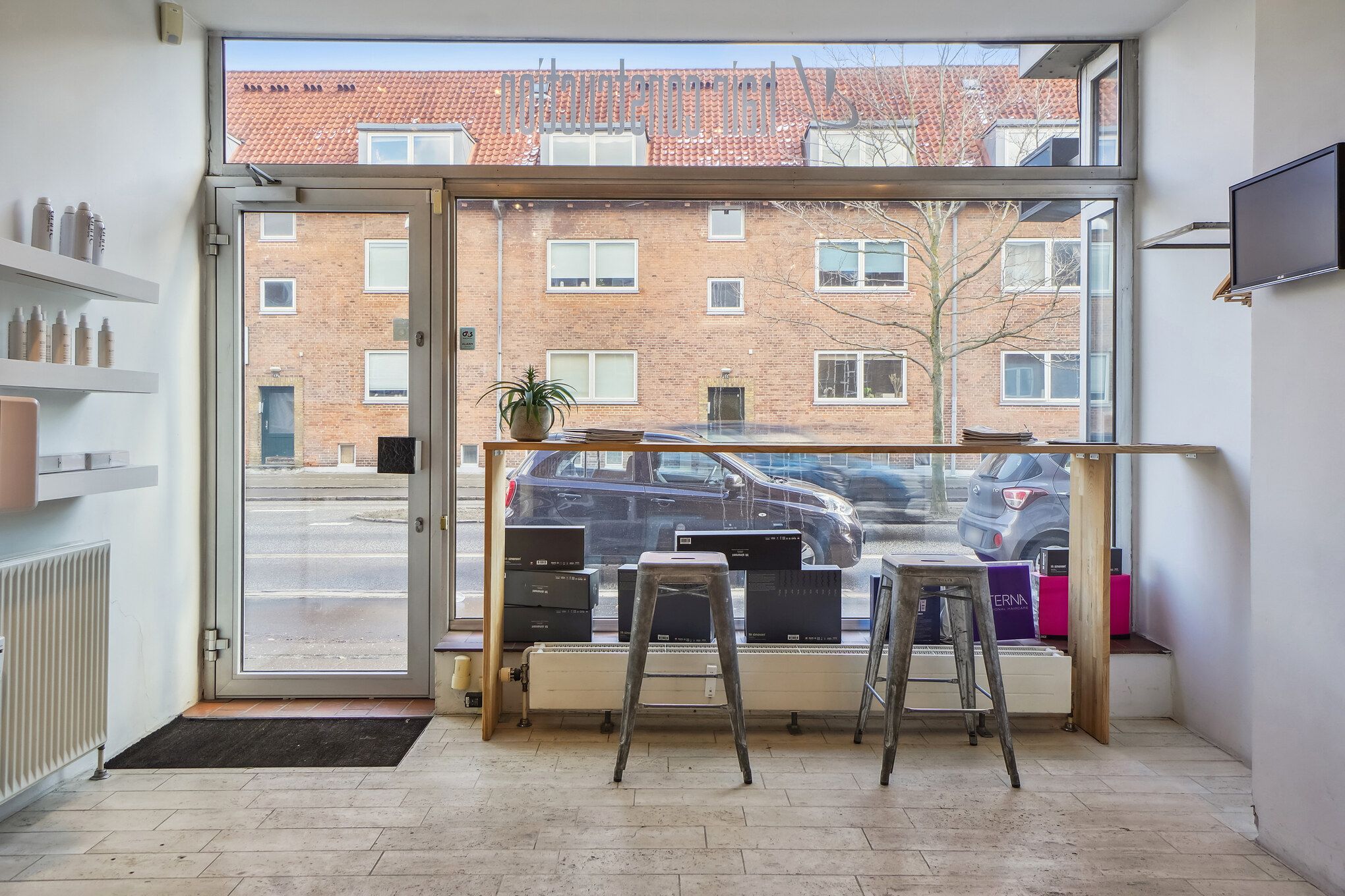 Opholdsrum med vinduer og stolpe, gulvbelægning og radiator, samt en vægbeskyttelse med en plante og smykker.