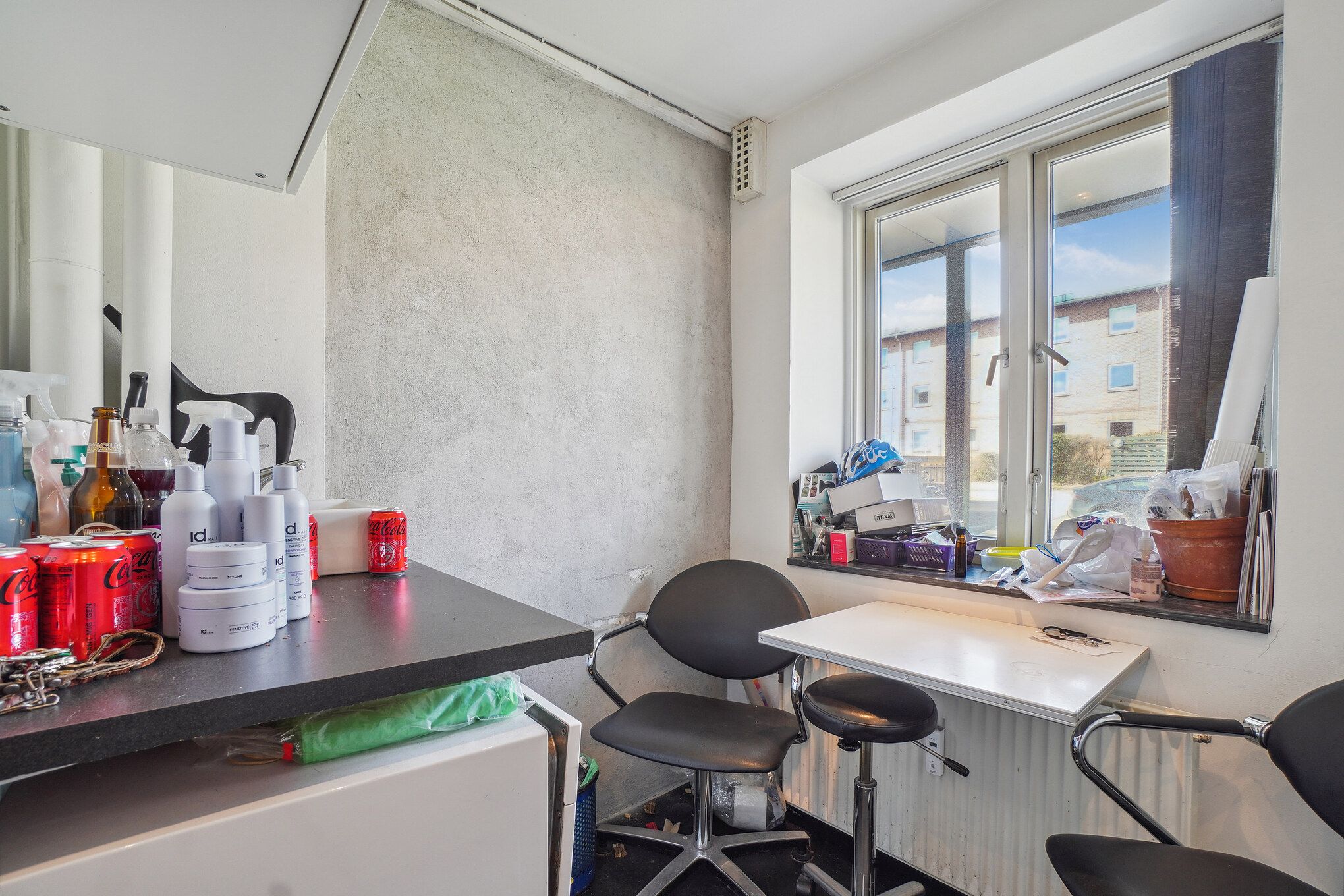 Et værelse med høj højde, møbler og produkter til hårpleje samt en stol og et bord med diverse genstande.
