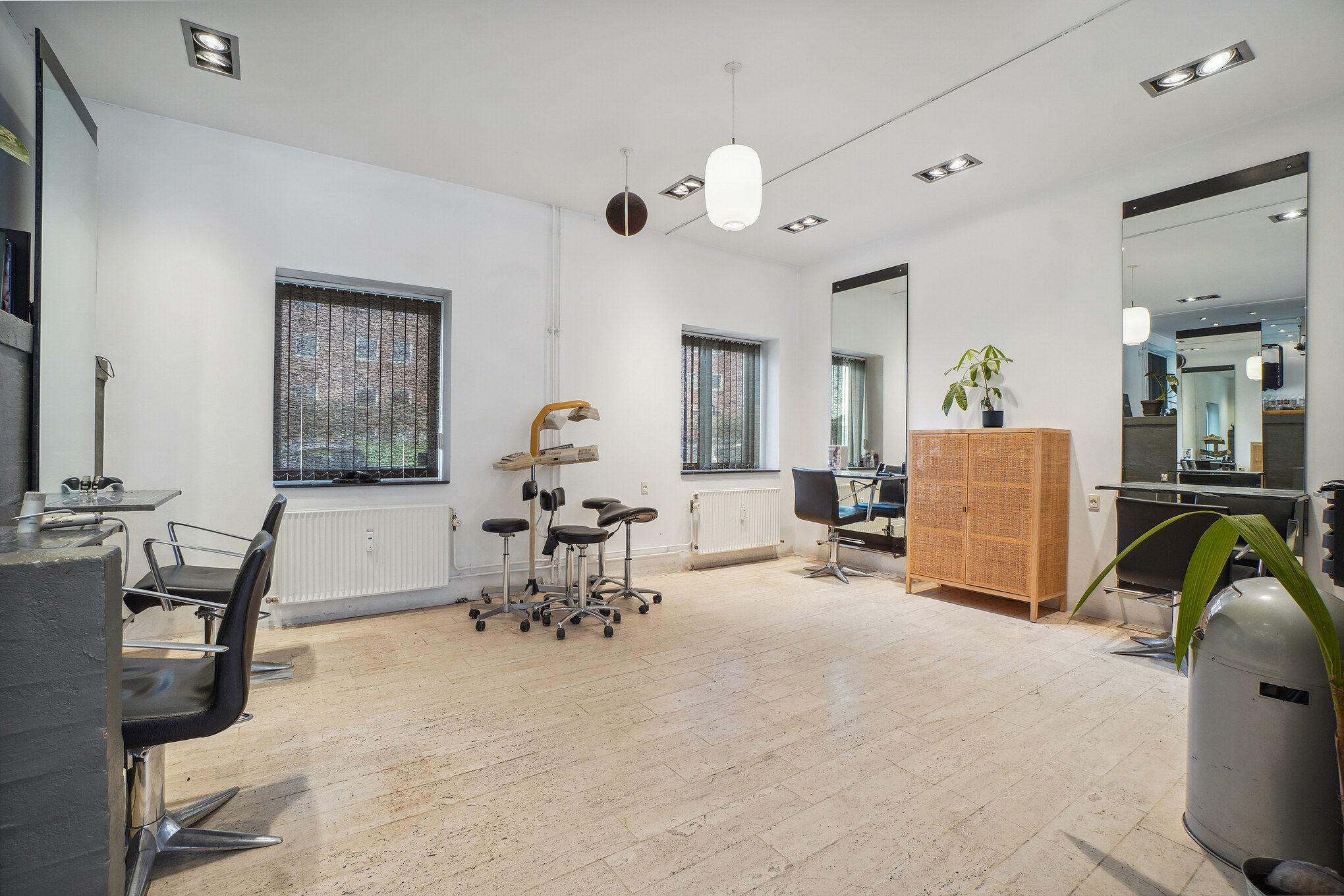 Her er en ny frisørsalon med lyse loftslampe og spejl samt moderne møbler og stole til både kunder og medarbejdere