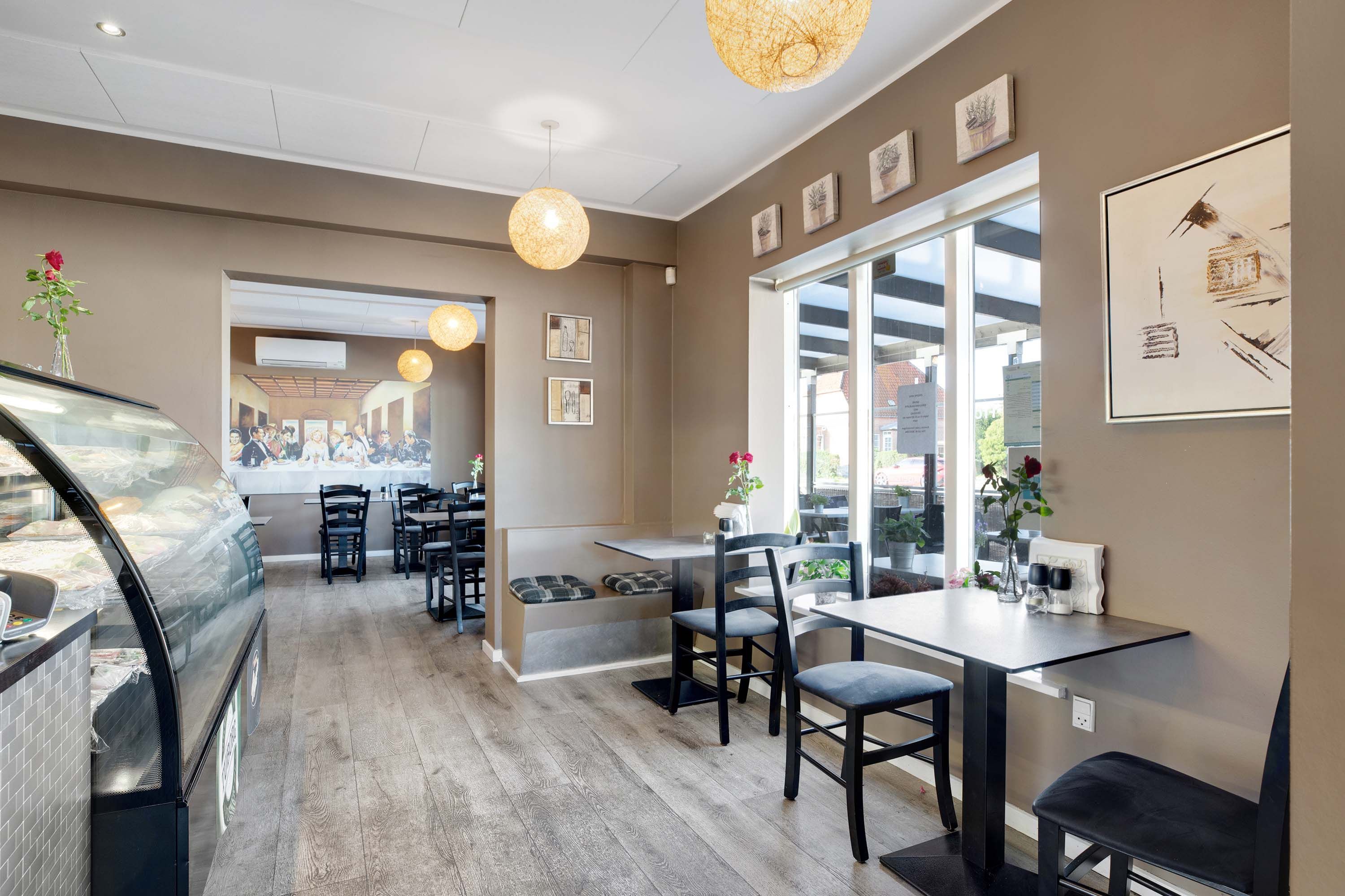 Et moderne indretningsdesign med bord og stole, en vindfælde og et køleskab med mad i det. Der er flere billeder på væggen