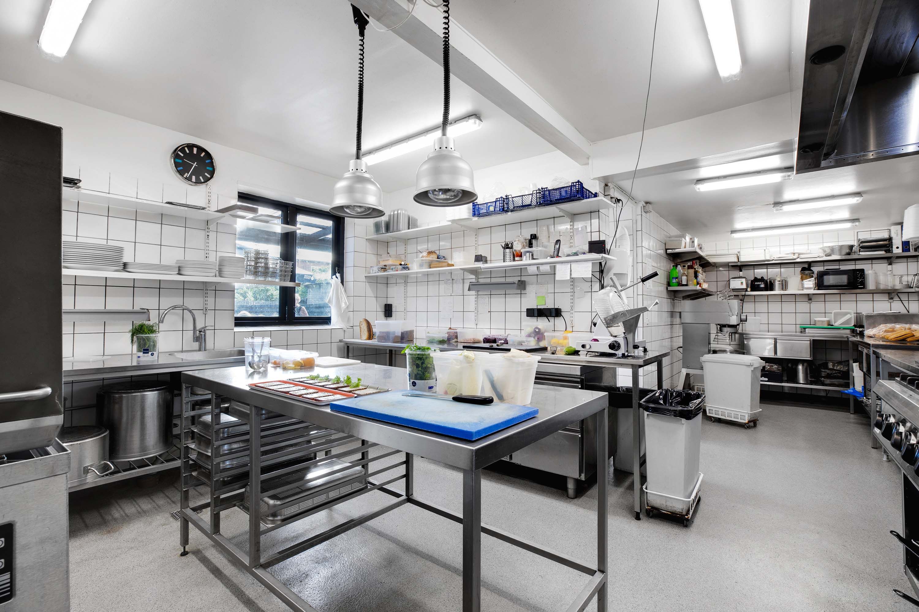 Et stort og moderne køkken med flere lyse og hygiejniske forhold og udstyret til at tilberede og servere mad