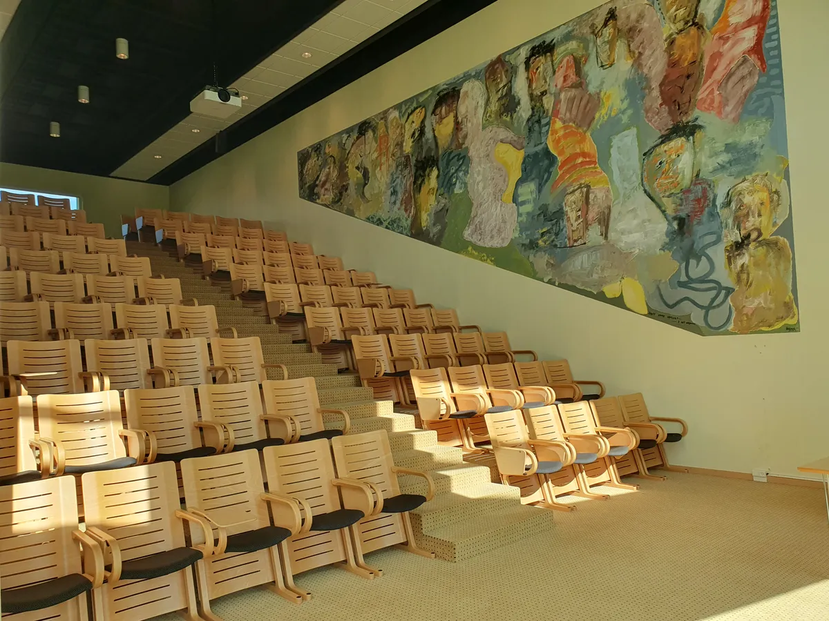 Rækker med lyse og moderne kontormøbler uden folk i salen med billedvæg og projektor