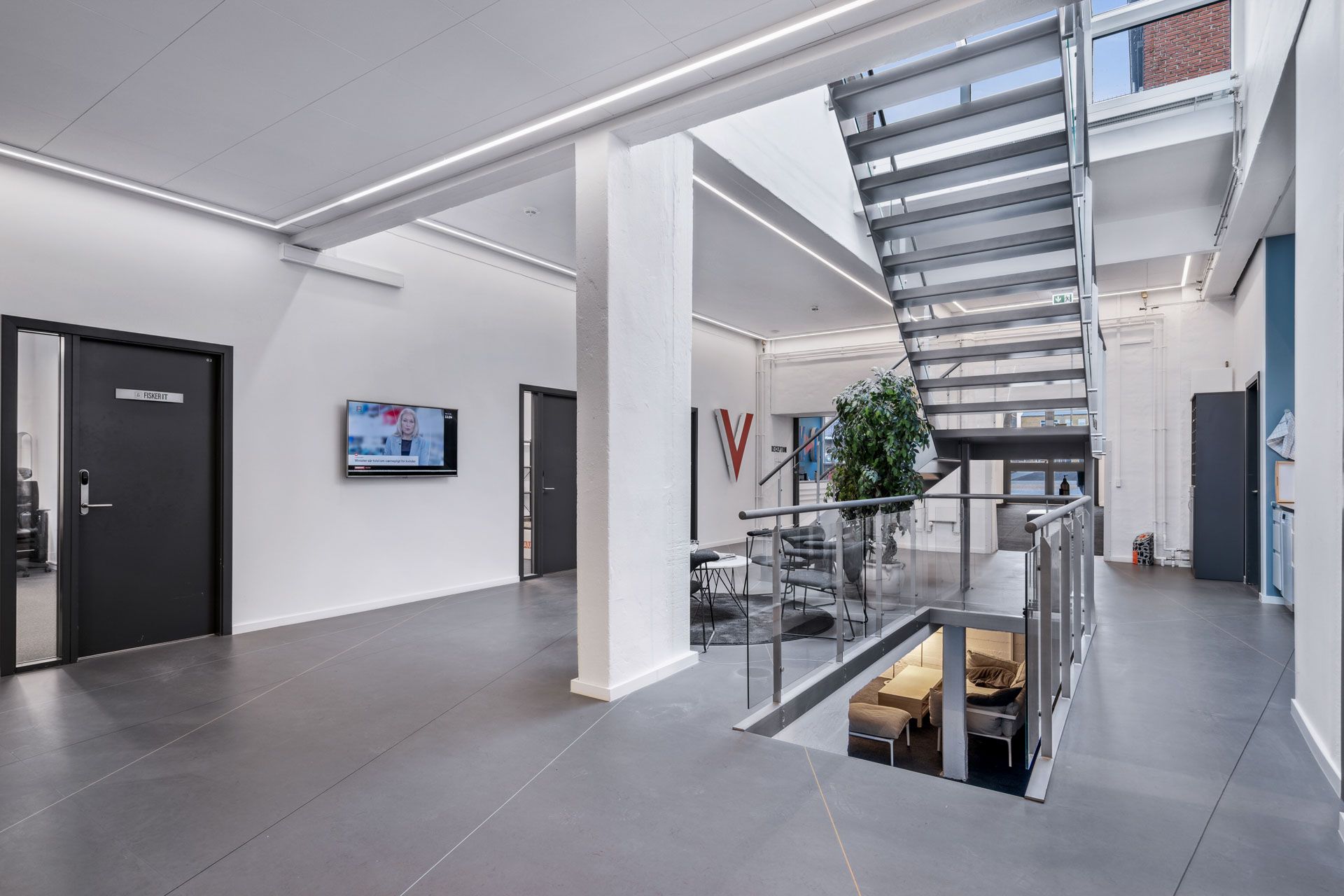 En kontorlokal med en TV-skærm, et skrivebord og en stige med et højdekammer med en sofa