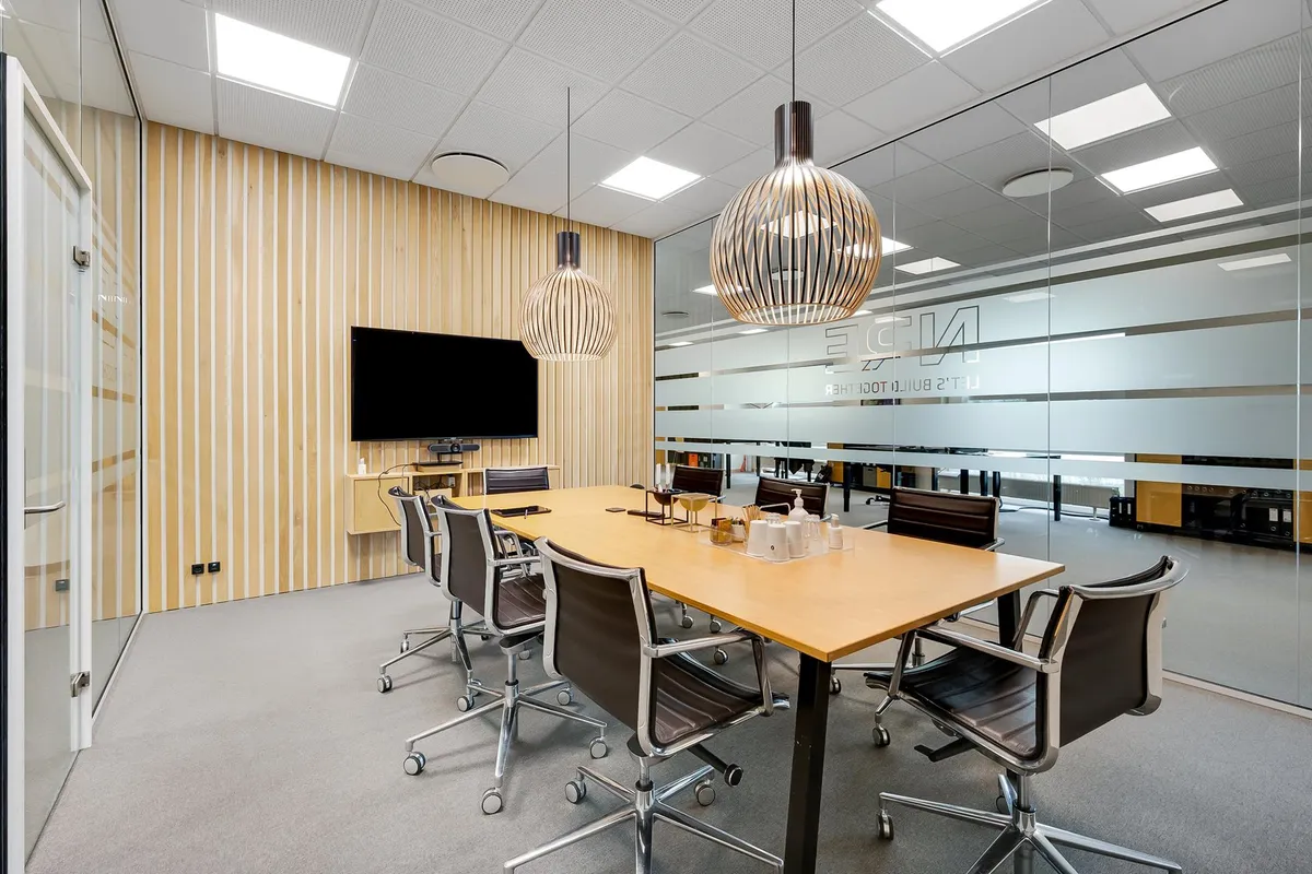 Kontor med lysegul gulvbelægning og møbler og lamper med geometriske former og tv-skærm på væggen