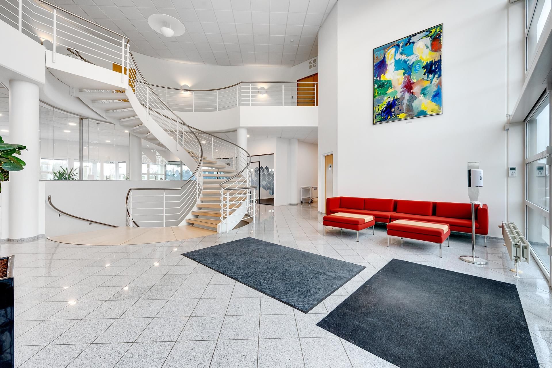 Kontorlokale med moderne design, hvidt loft, lysegul gulv og moderne møbler. Loftsvinduer, slank spiraltrappe og farverige