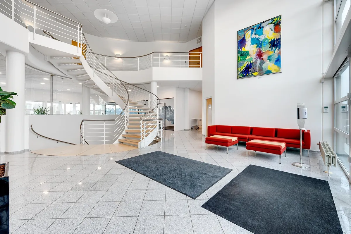 Kontorlokale med moderne design, hvidt loft, lysegul gulv og moderne møbler. Loftsvinduer, slank spiraltrappe og farverige