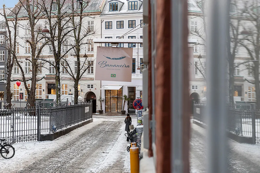Forside af restauranten Bananaeira med skilt og sne på jorden og træer med sne i København